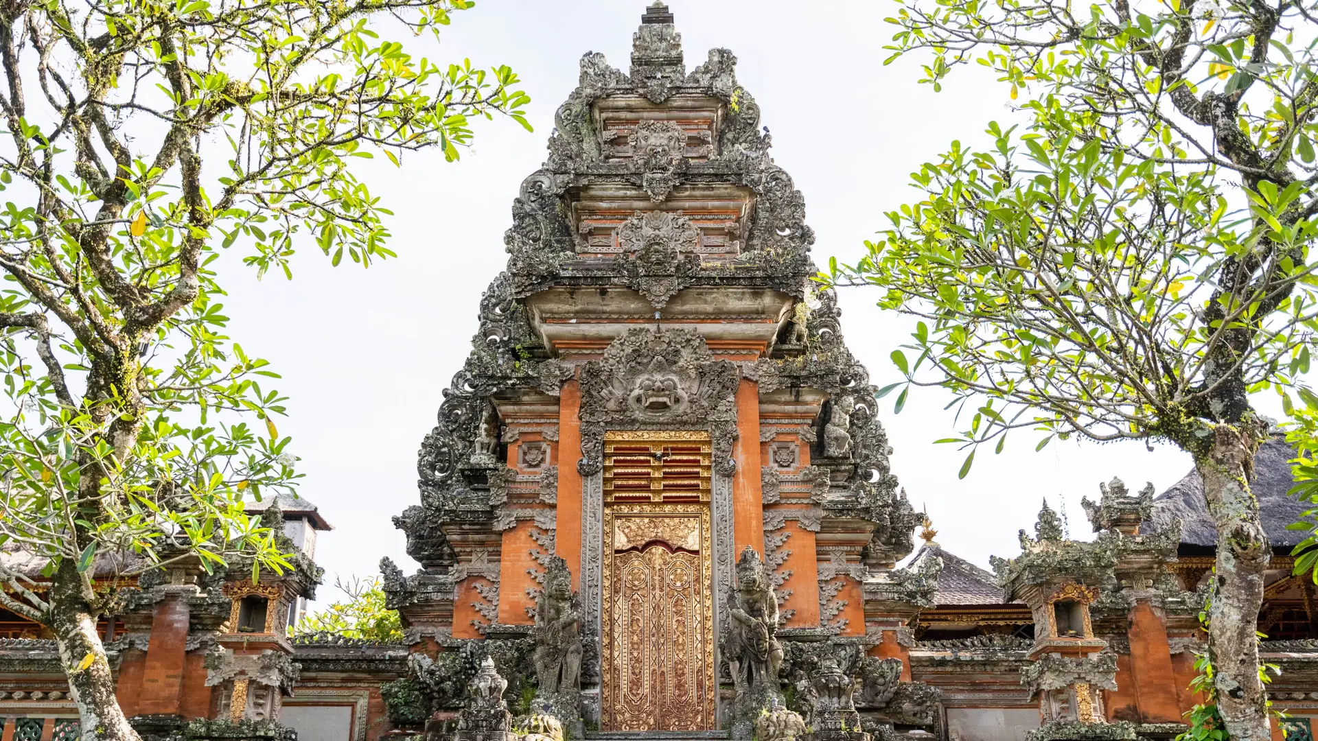A carved stone temple doorway framed by trees in Ubud