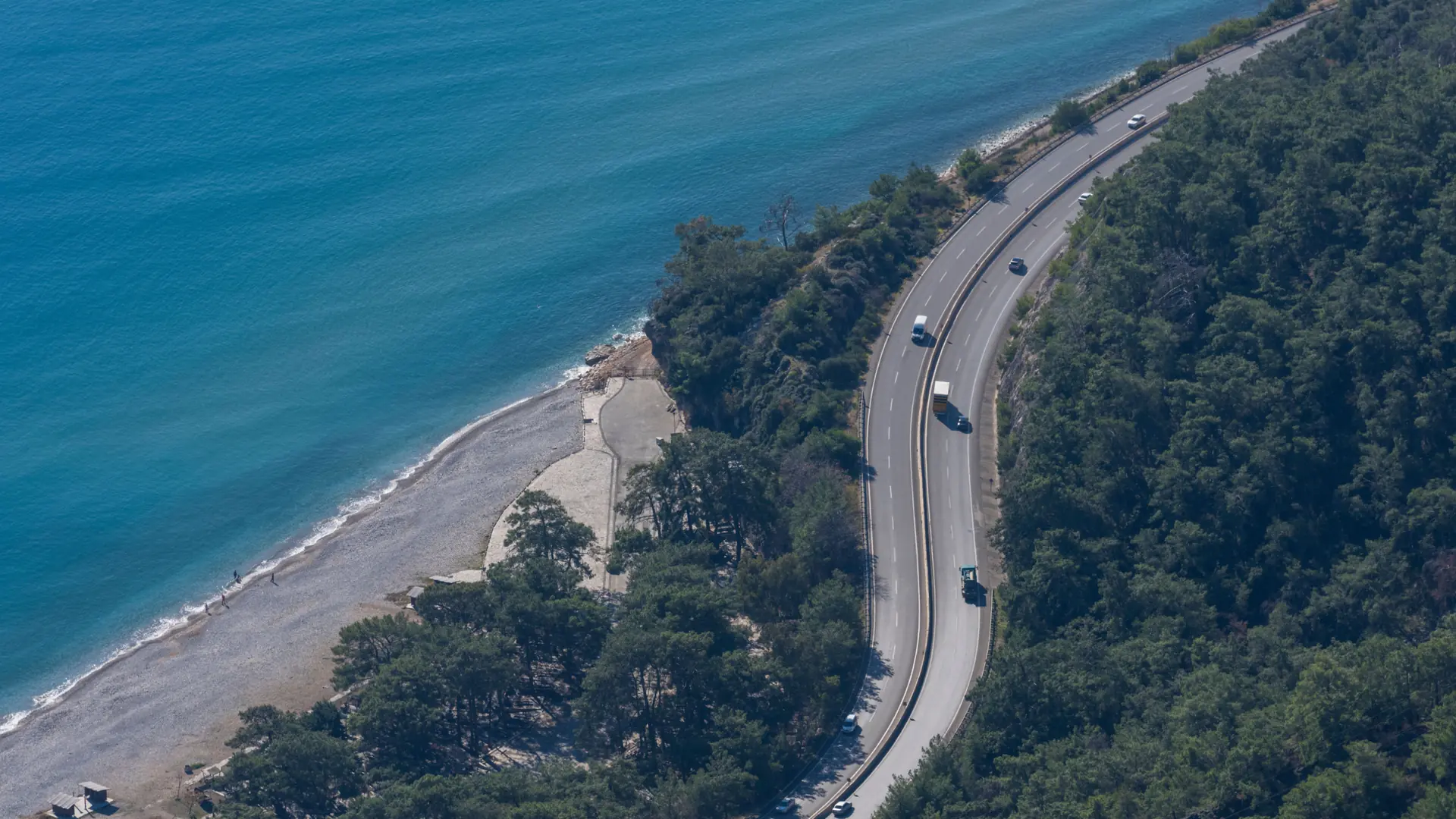 Scenic Turkish coastal road above vivid blue sea and forested mountains