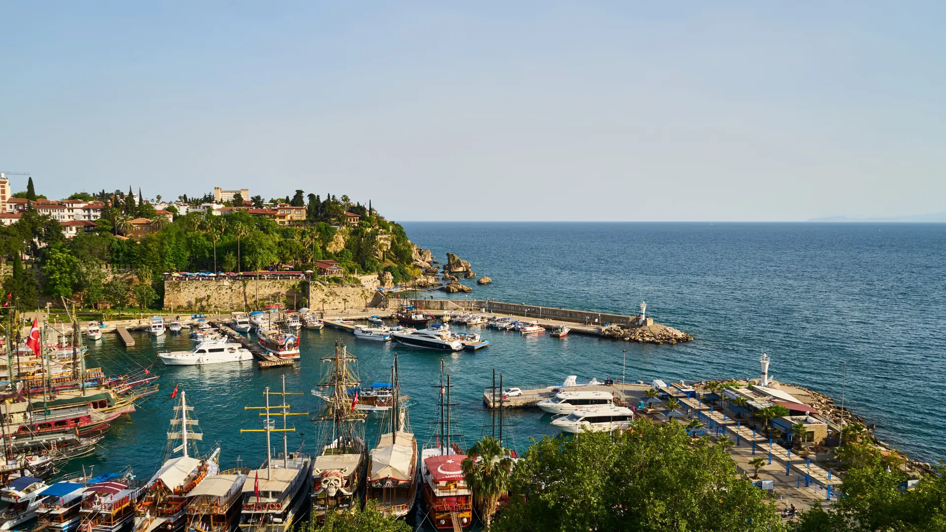 Sunny Antalya old harbour below Kaleici walls with blue Mediterranean water and Taurus Mountains