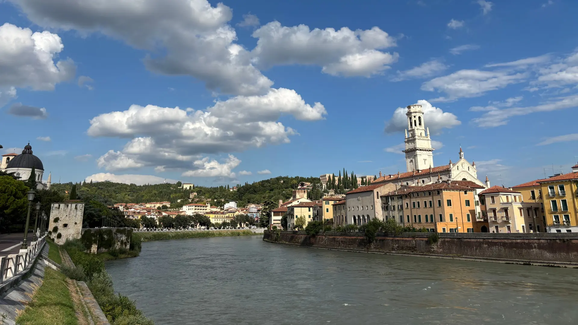 The Adige River and historic riverside buildings in Verona beneath a blue sky.