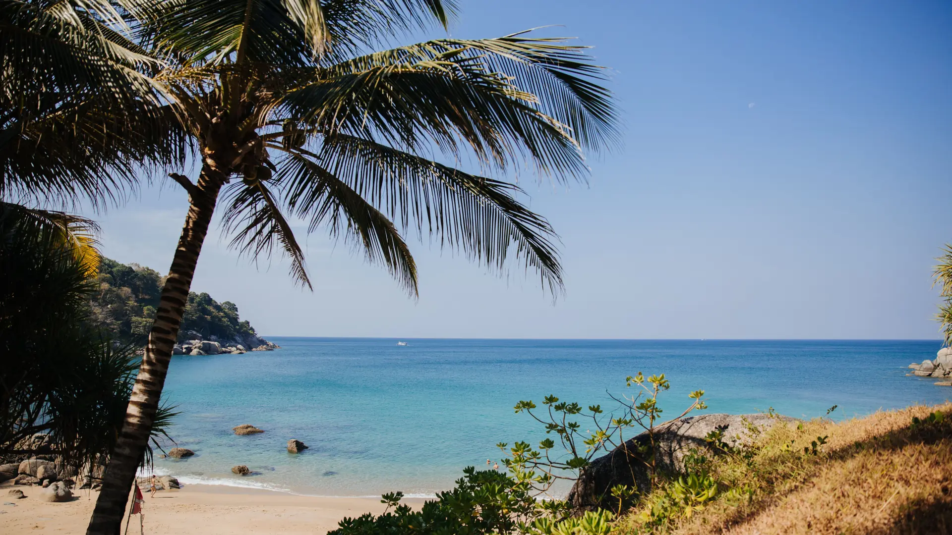 A quiet Phuket beach with pale sand and glassy blue water