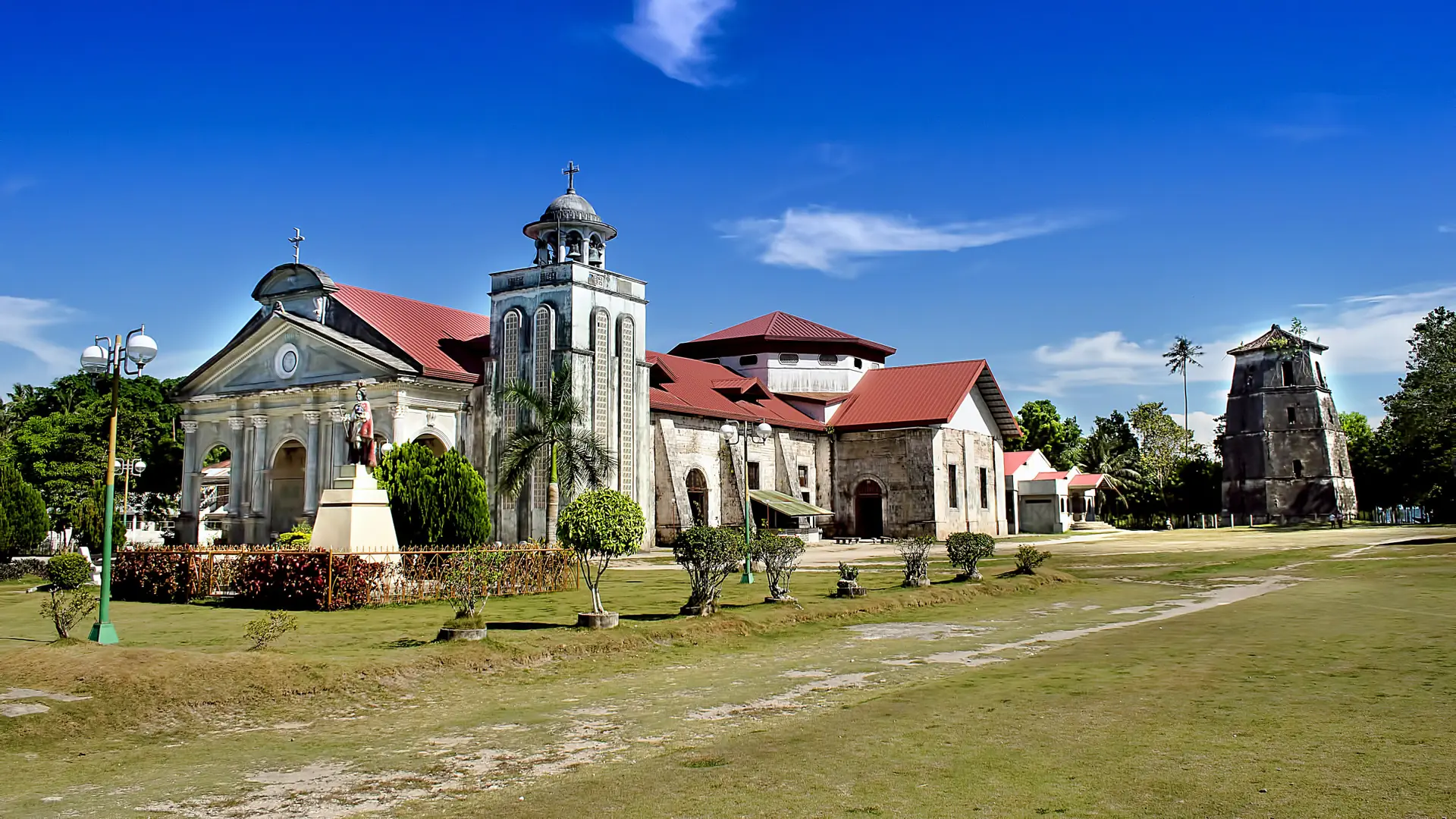 San Agustin church and its old stone watchtower in Panglao town under a deep blue sky