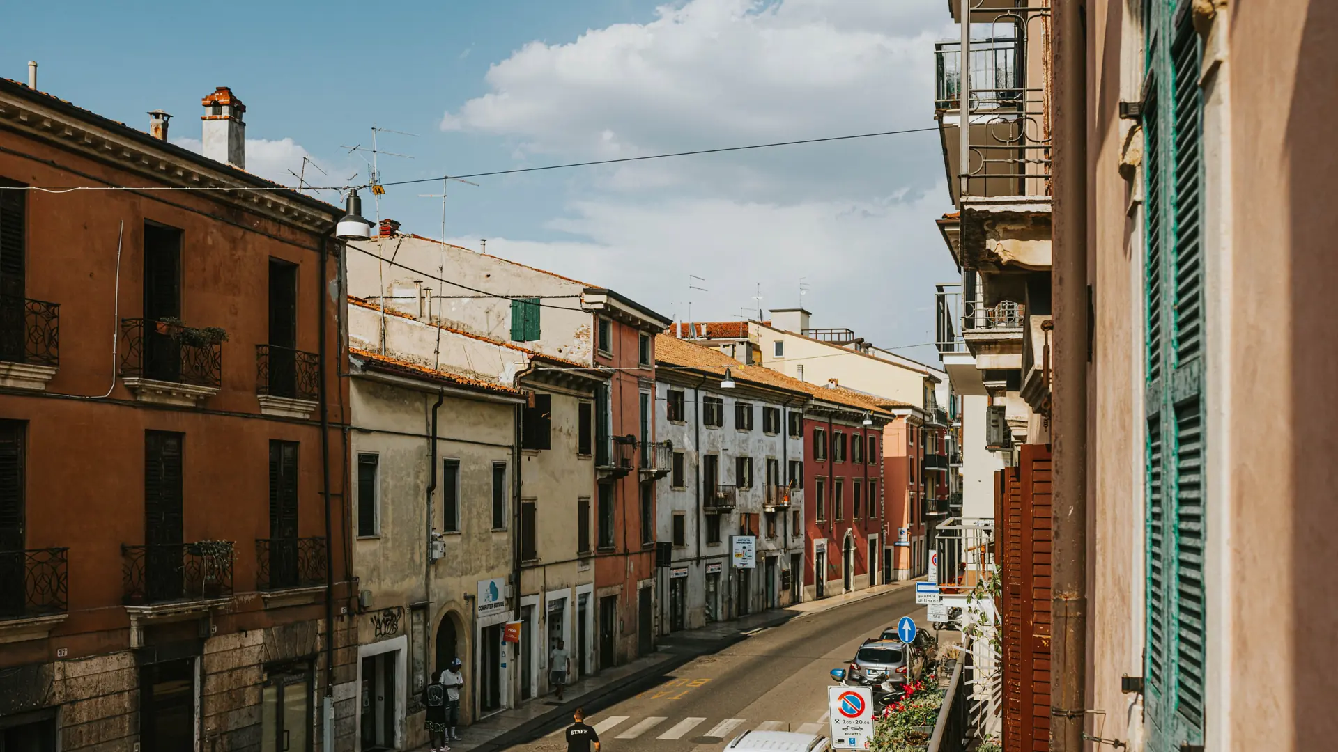 a sunlit Veronetta street lined with terracotta and cream façades