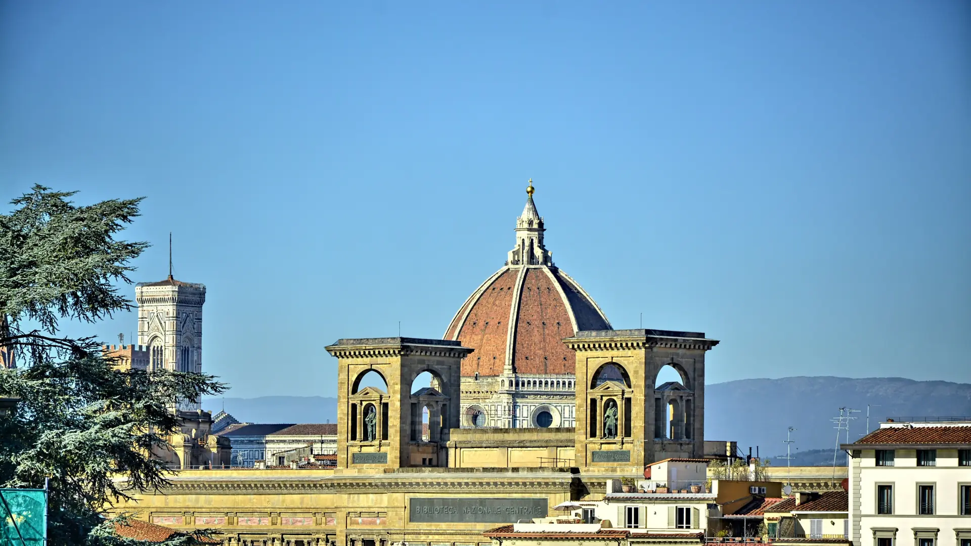 the Duomo's red-tiled dome rising against a clear blue sky in Florence