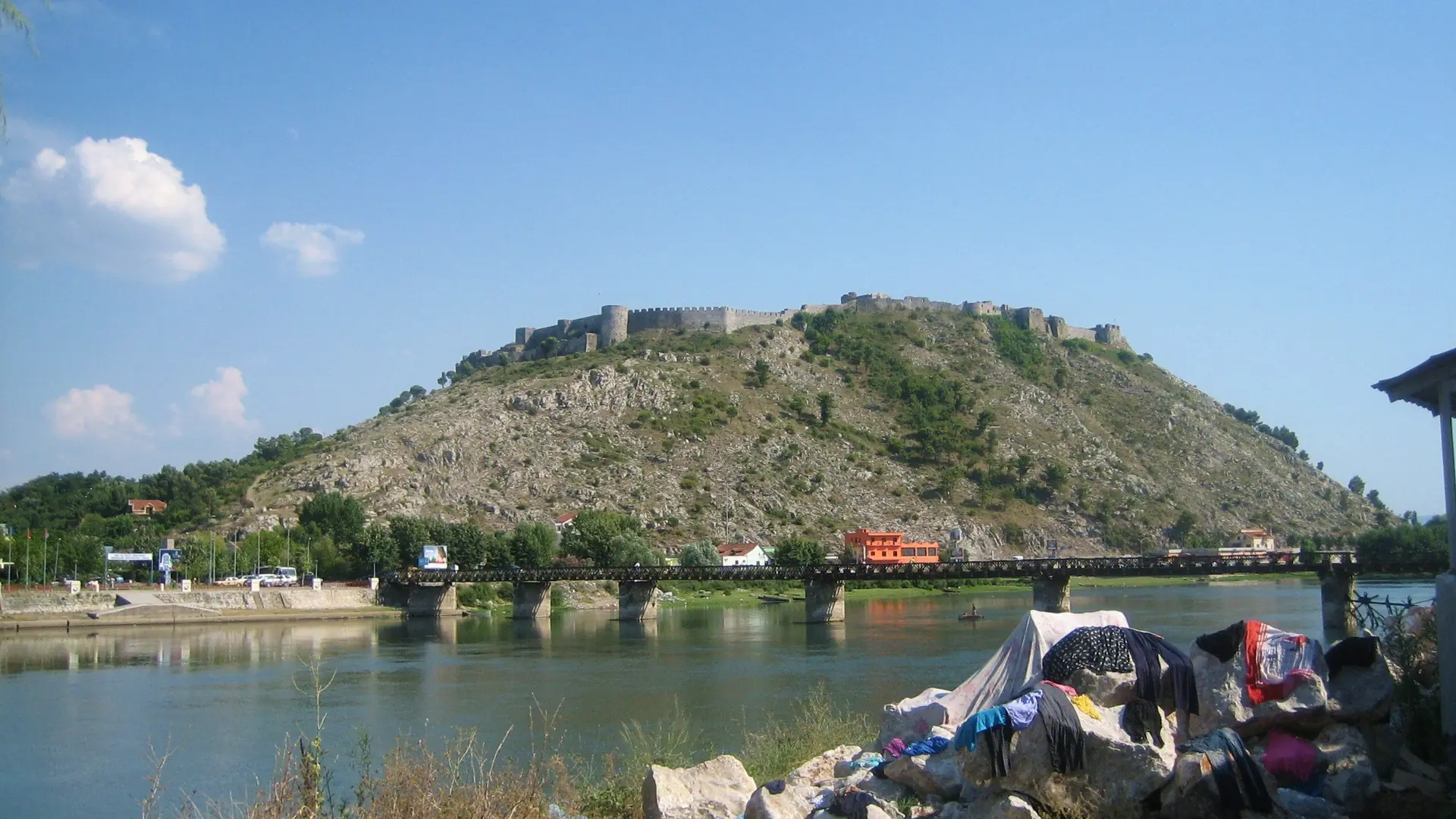 Rozafa Castle's hill rising above the Buna river and its bridge at Shkodër under a clear blue sky