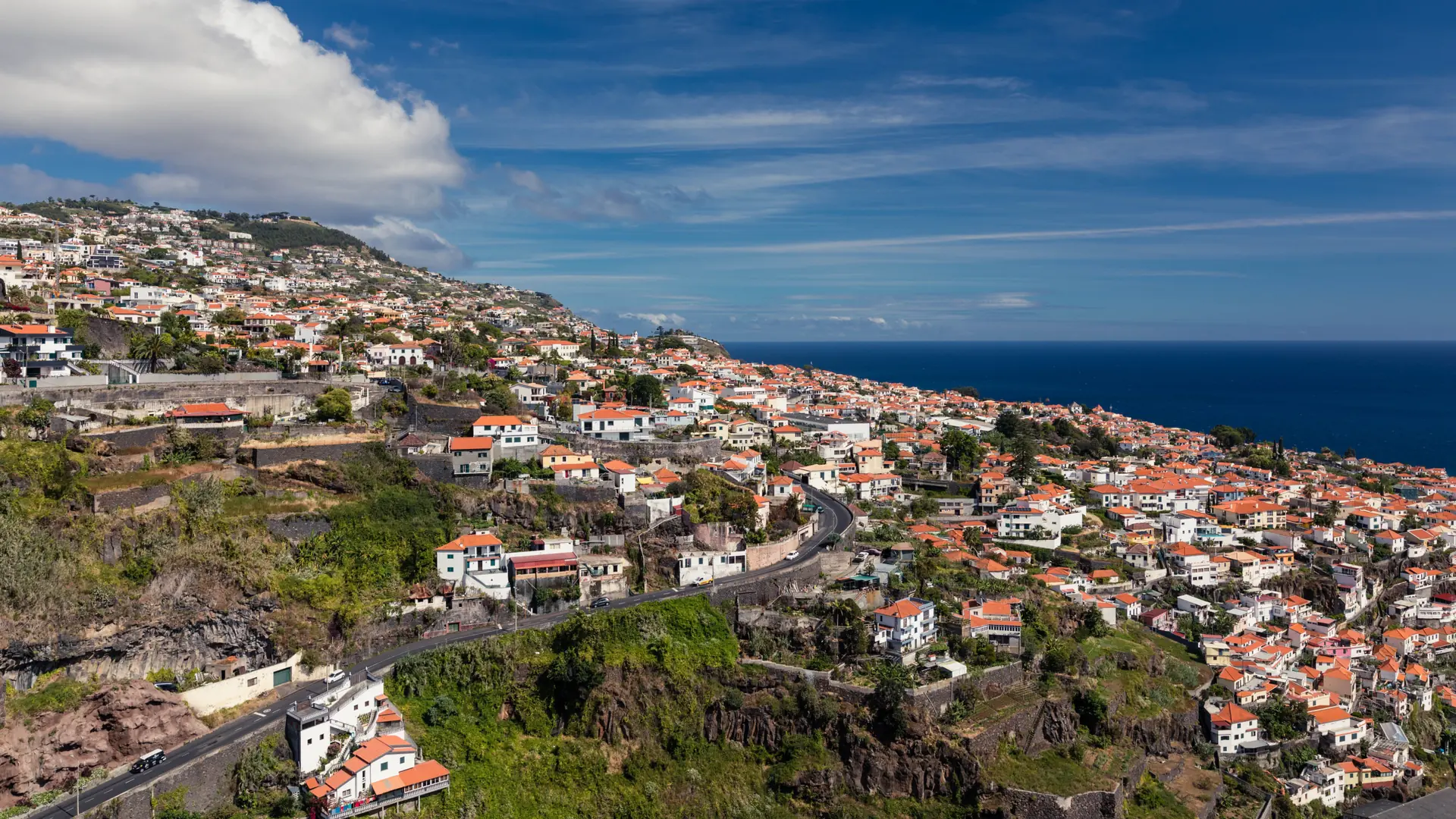 Red-roofed houses and green terraced hillsides above the Atlantic in Funchal, Madeira