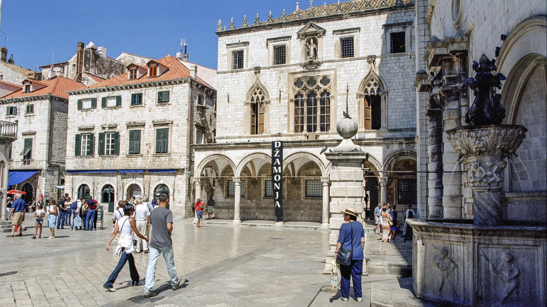 Sponza Palace and the fountain at the start of Stradun, Dubrovnik's main street, under a clear blue sky