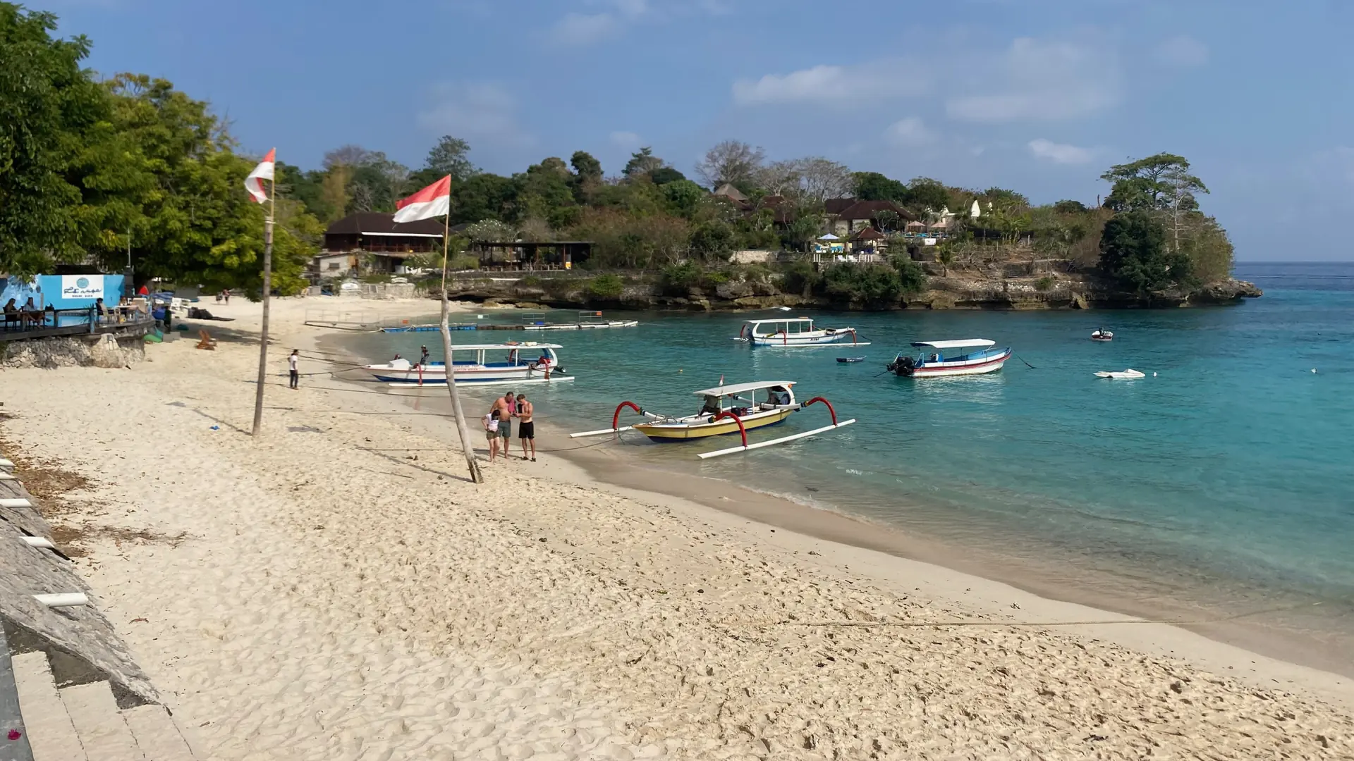 Mushroom Bay on Nusa Lembongan, with sunny sand, outrigger boats and its wooded headland