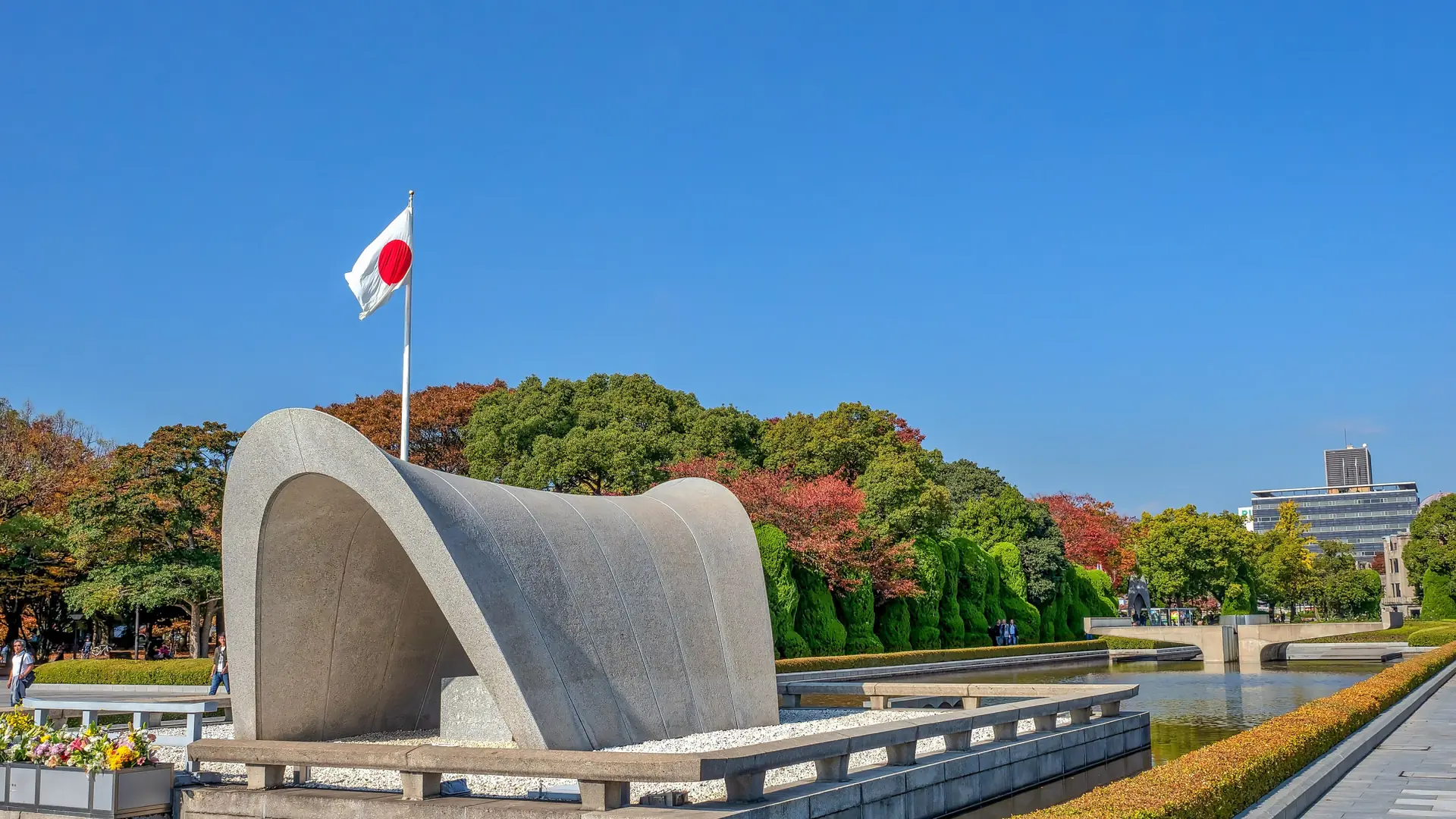 The Cenotaph and memorial pond beneath a clear blue sky in Hiroshima Peace Memorial Park