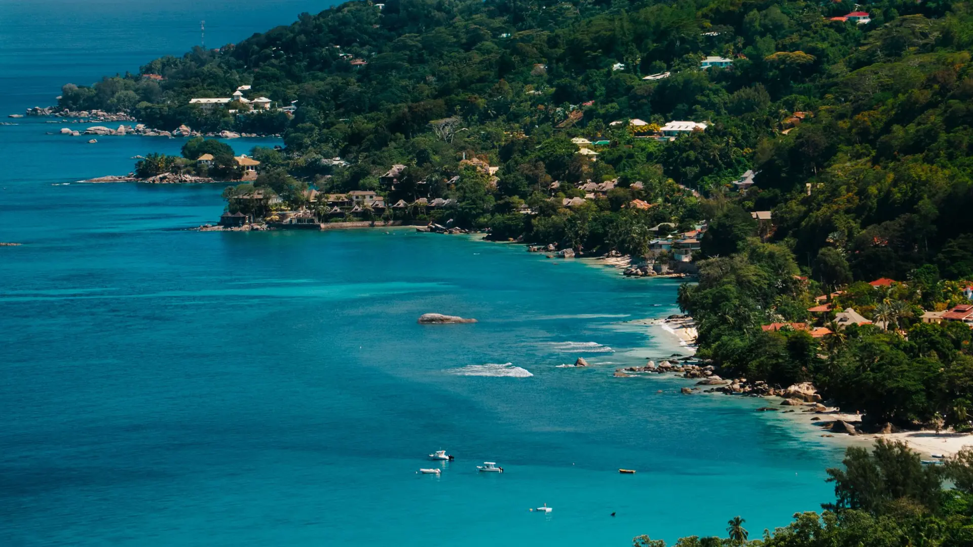 Turquoise water and wooded shore along Beau Vallon bay