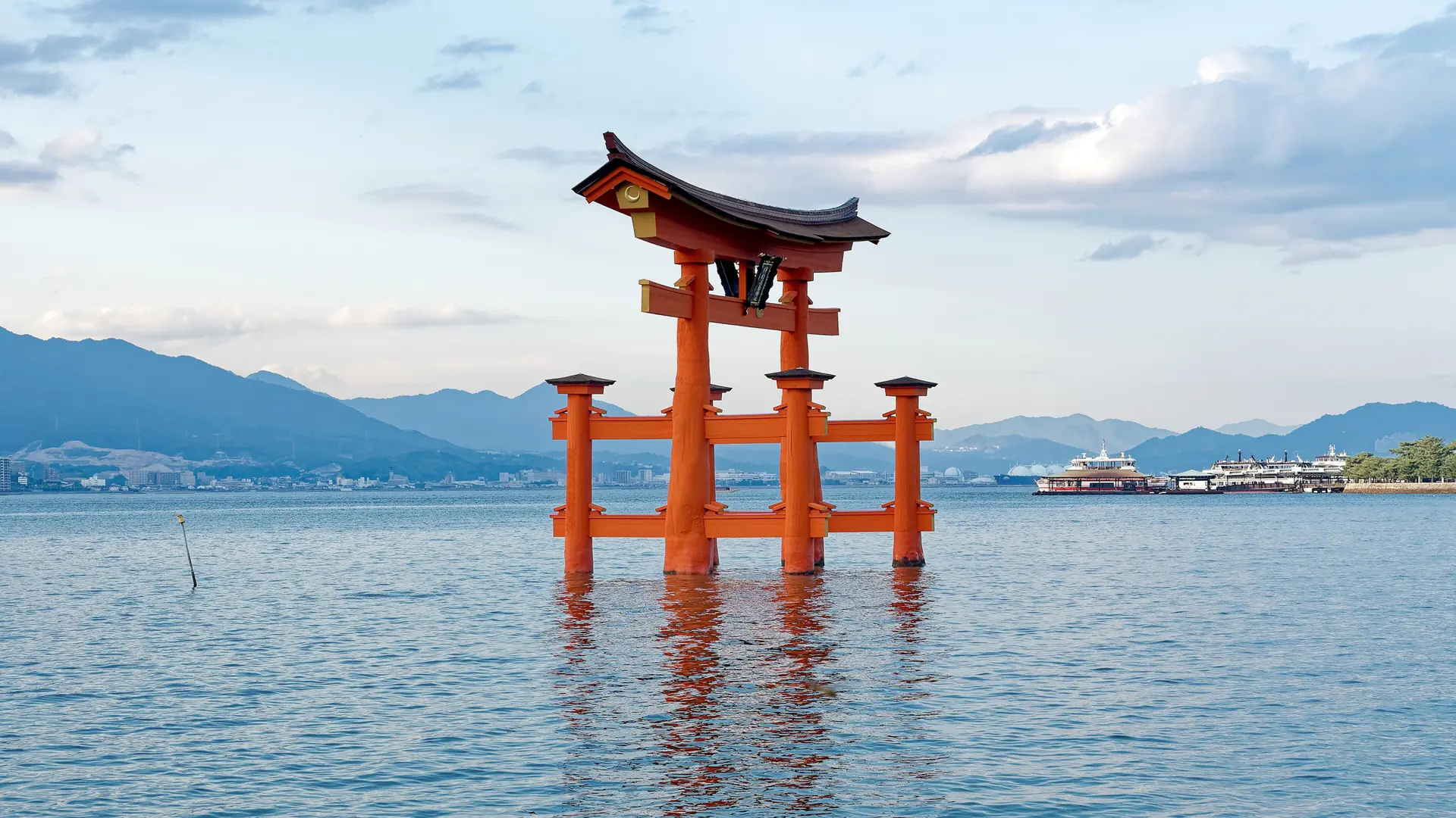 Itsukushima Shrine’s vermilion great torii standing in blue water off Miyajima.