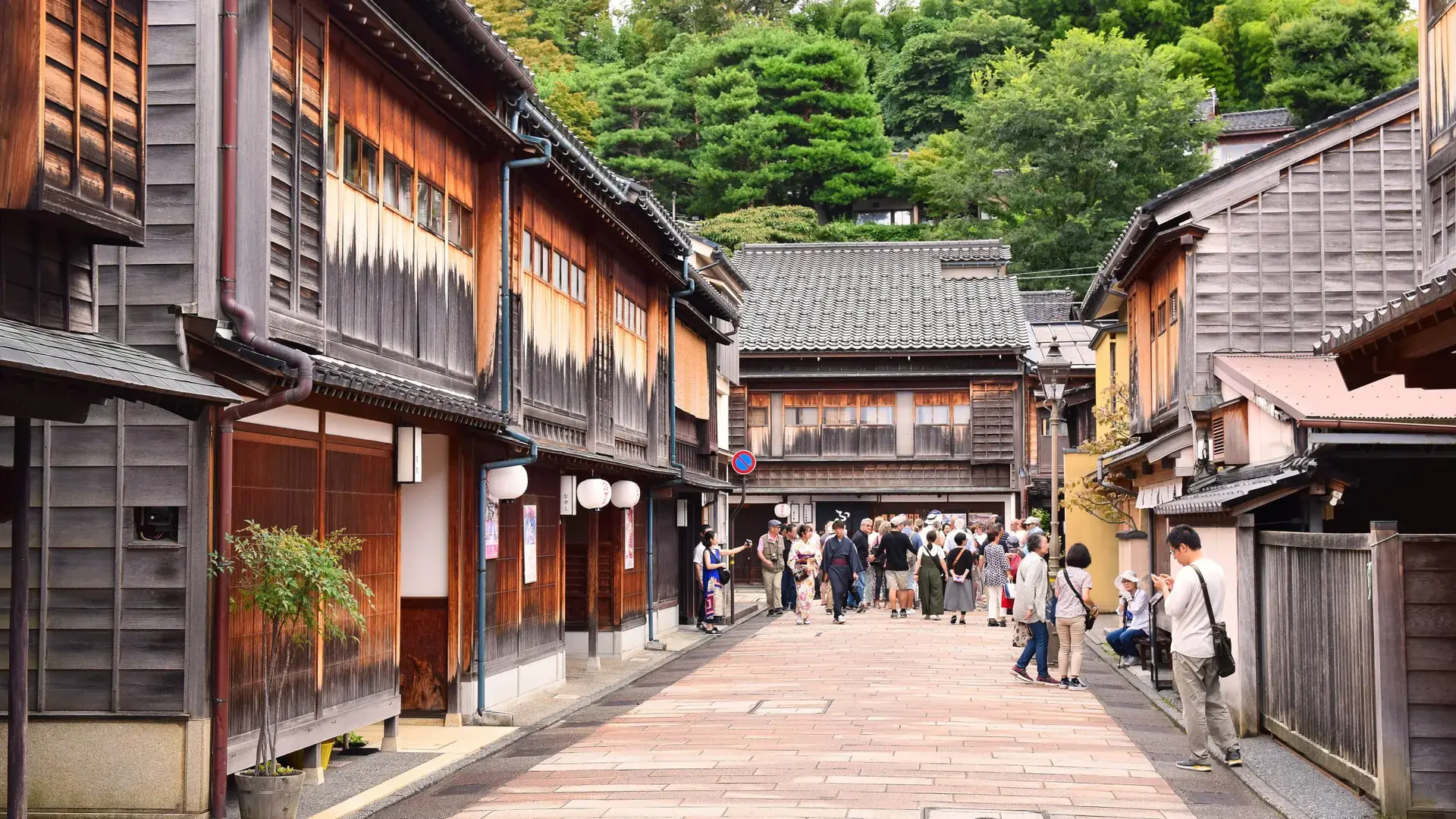wooden teahouses lining Higashi Chaya's broad stone street in warm sunlight