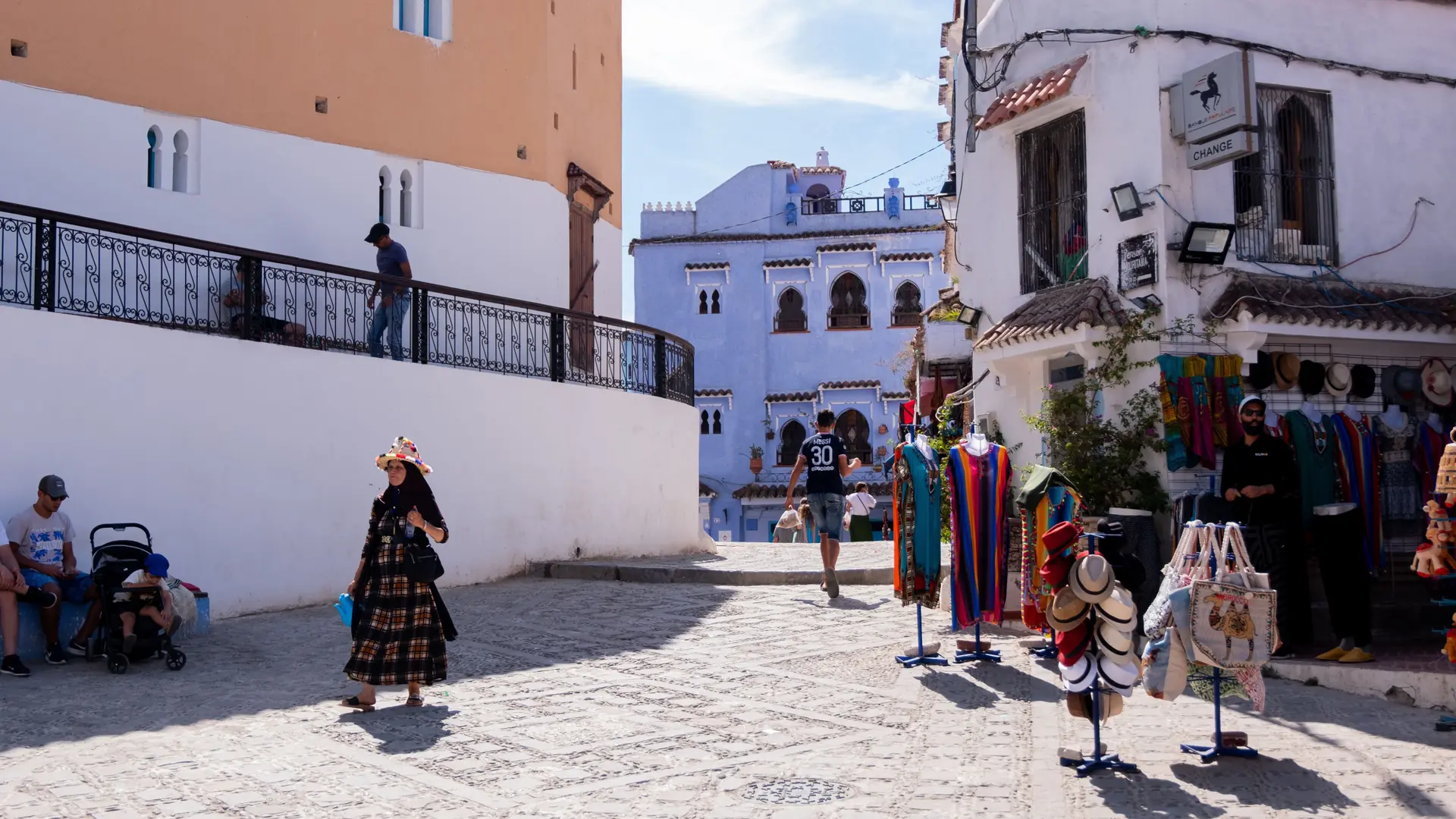 Sunlit Chefchaouen street with blue buildings and craft stalls