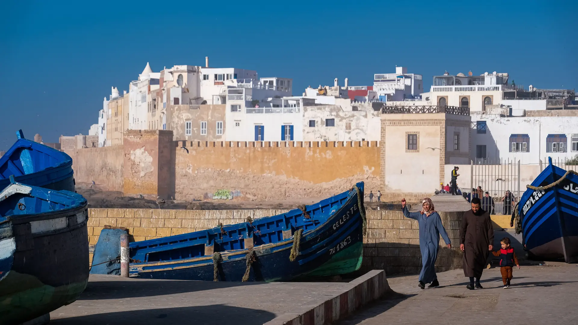Fishing boats and sunlit sea walls at Essaouira harbour