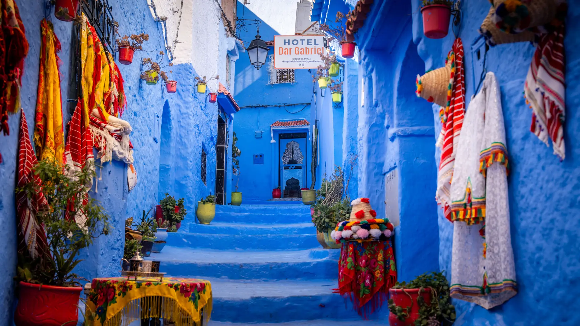 Vivid blue Chefchaouen medina lane with colourful textiles