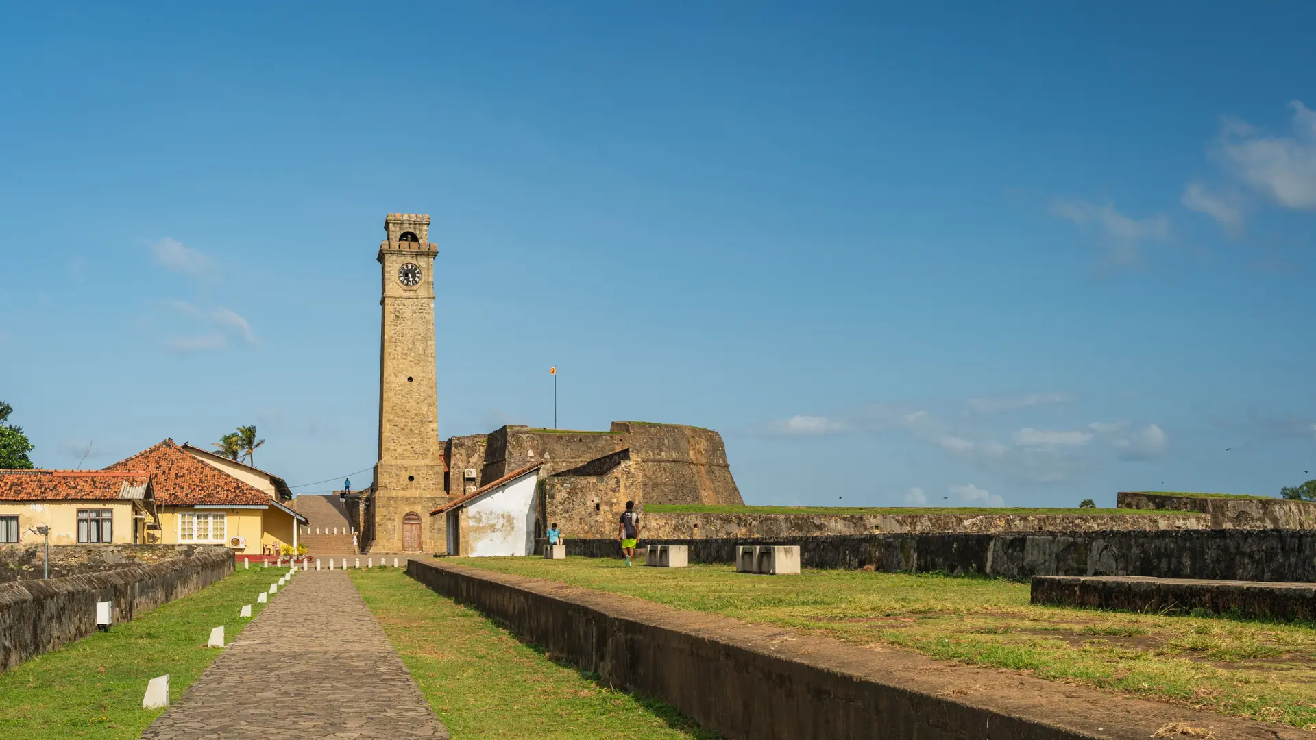Galle Fort clock tower and sunlit stone ramparts under blue sky