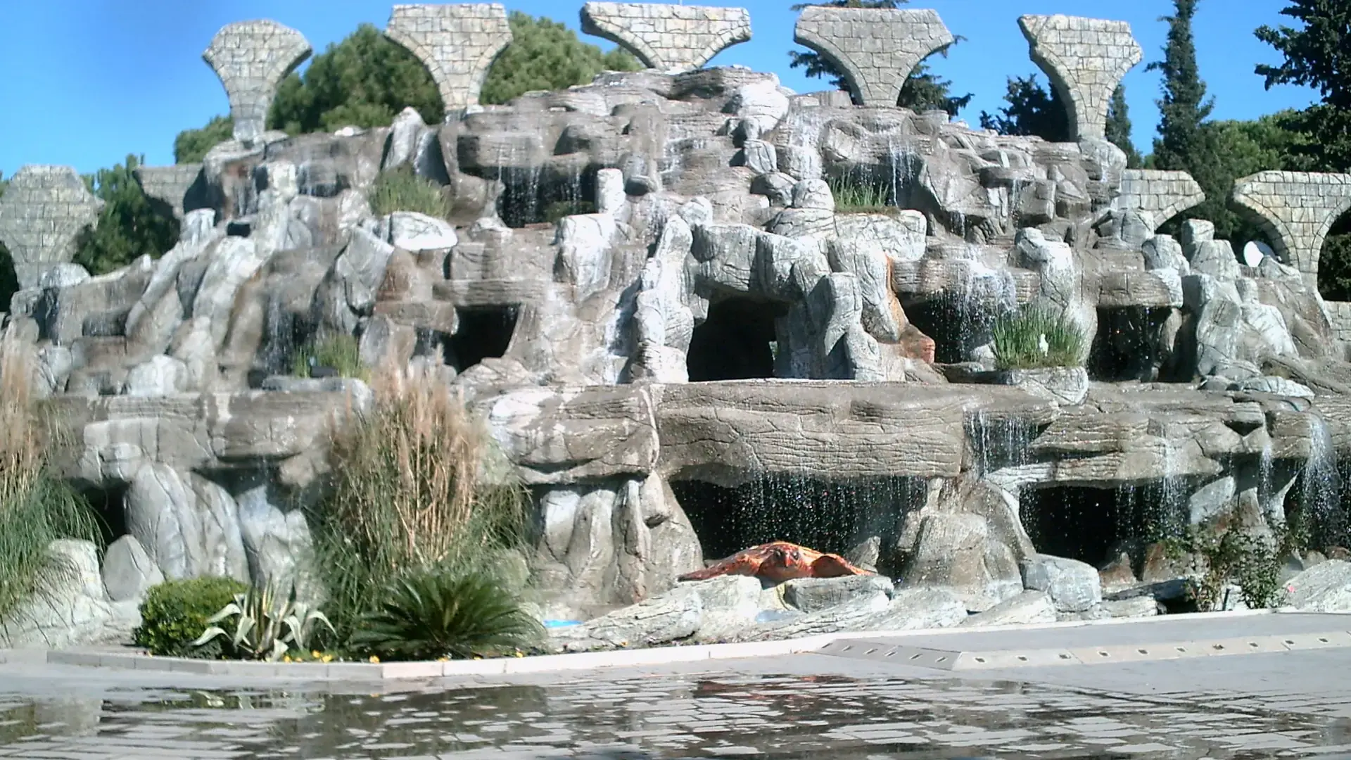 Decorative stone fountain and landscaped public space in central Belek under a blue sky