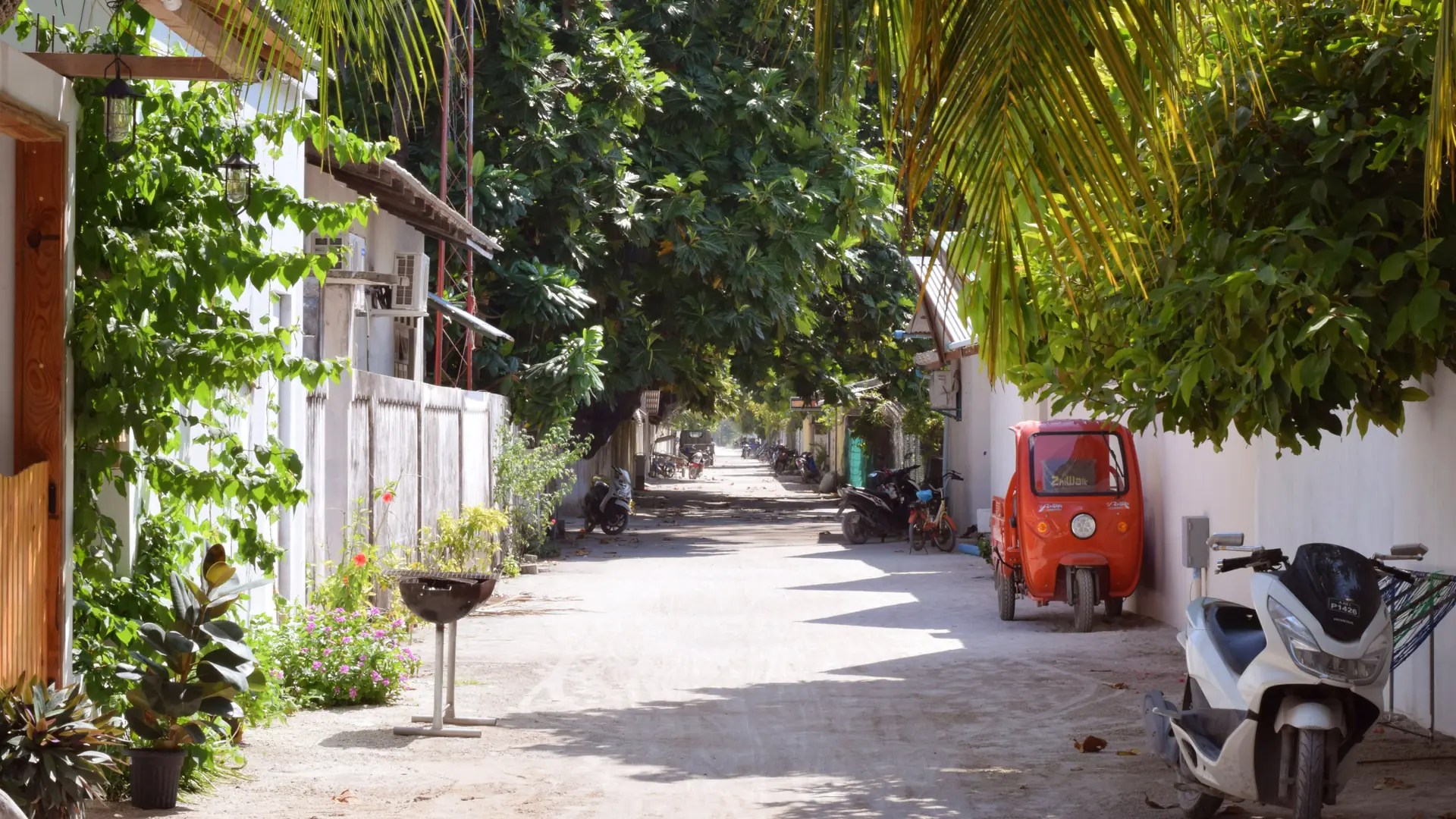 Shaded village street with parked motorcycles in Thoddoo, Maldives