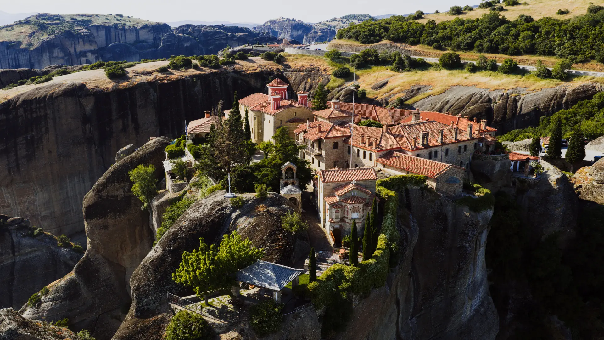 A Meteora monastery and red roofs set between immense sunlit rock pillars above Kalambaka