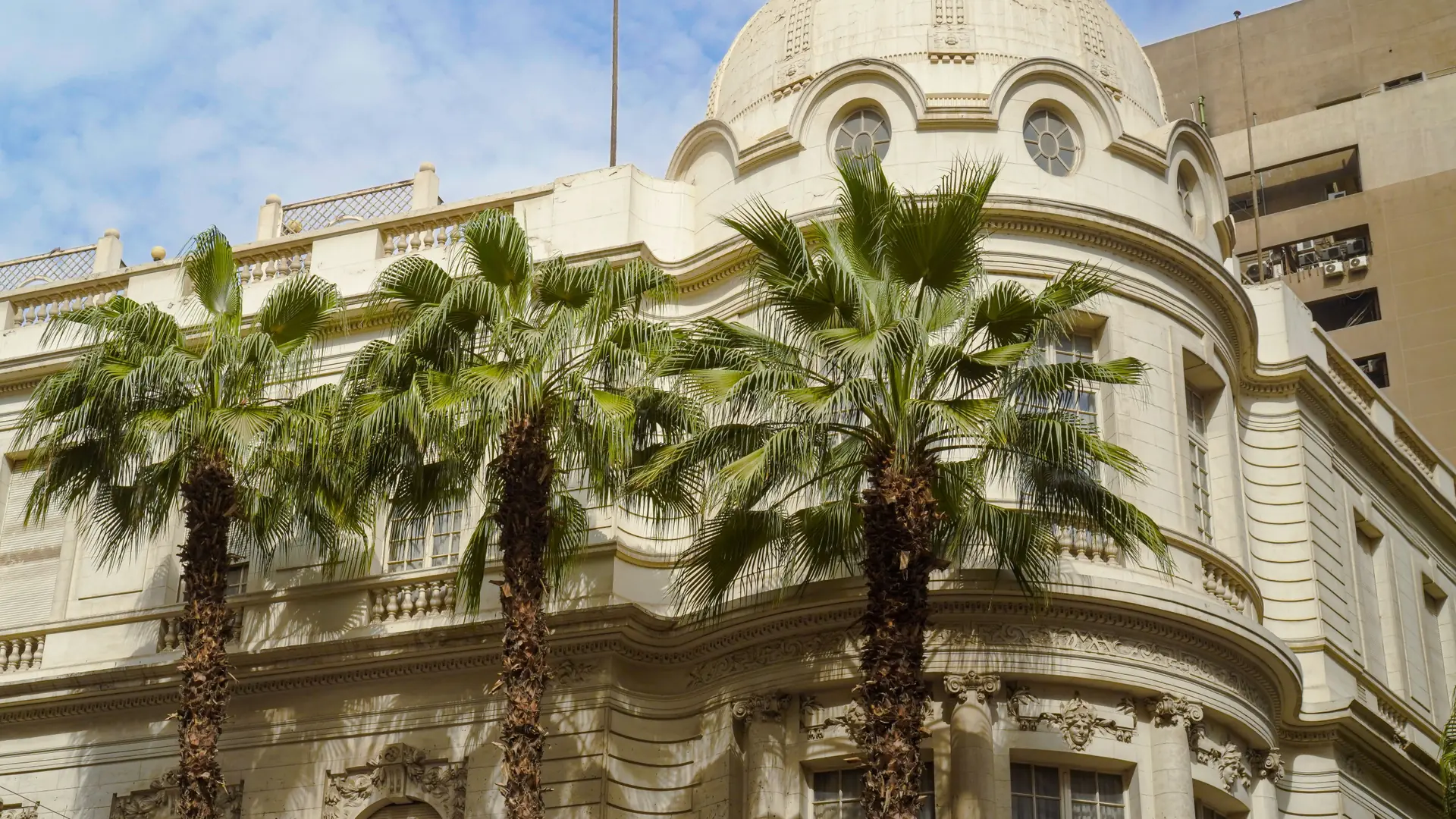 Historic Cairo building with palms and a bright blue sky