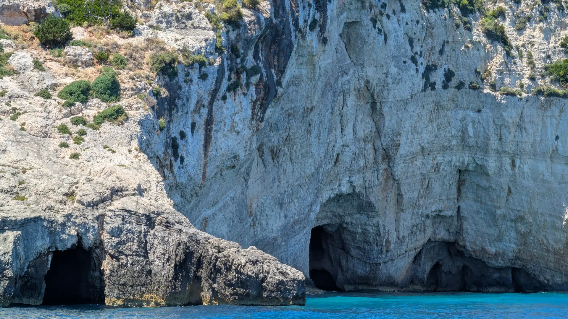 A small boat beside the pale limestone walls and blue caves of Zakynthos