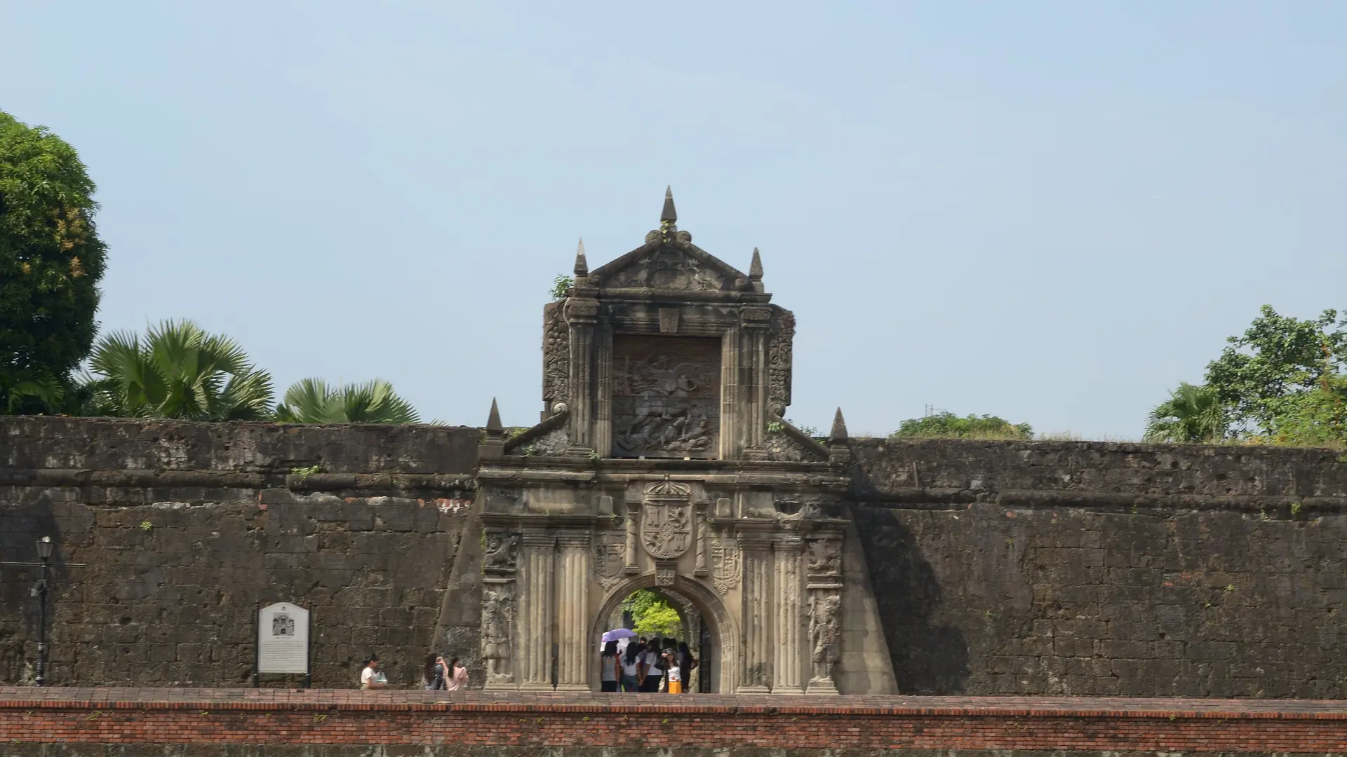 Fort Santiago’s carved stone gateway and walls beneath a pale blue sky in Intramuros
