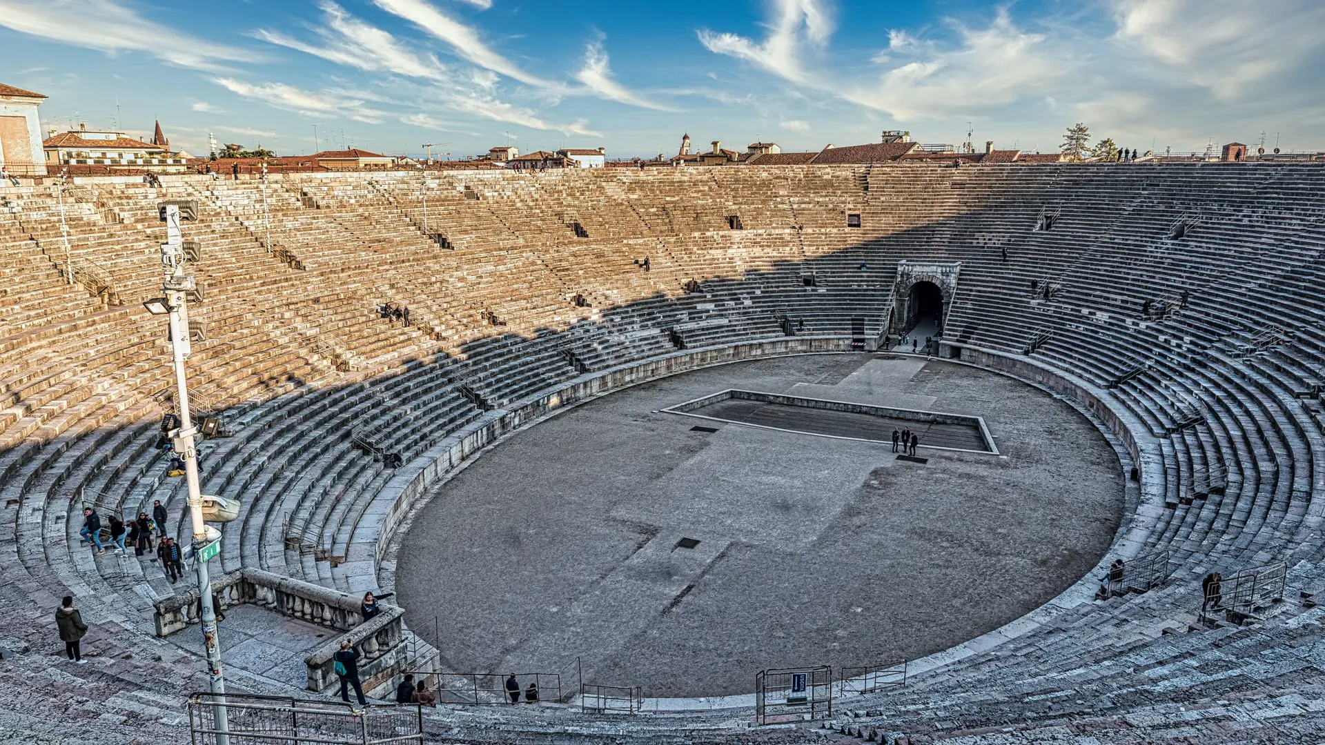 the Verona Arena's pink-white stone tiers under a vivid blue sky