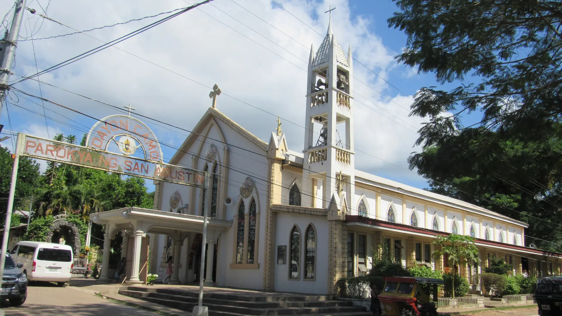 San Agustin Church and its bell tower beside a tree-lined street in Coron town
