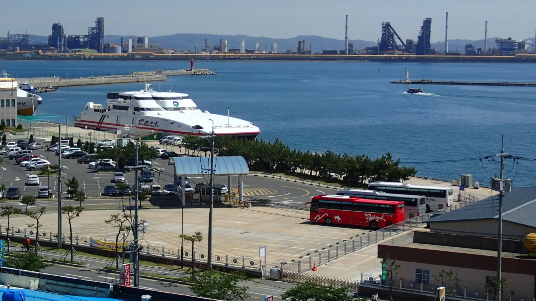 A passenger ferry at Pohang port in 2014, with blue water and steelworks across the bay; a wider-city view