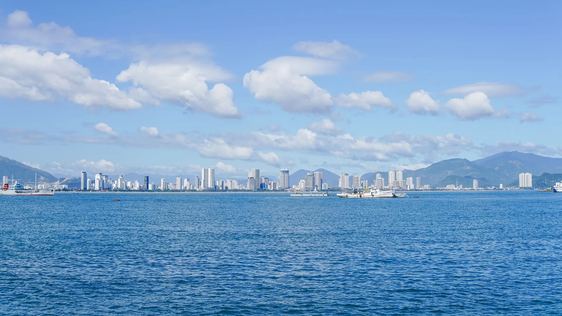 Boats on the blue bay with the wider Nha Trang city skyline beyond