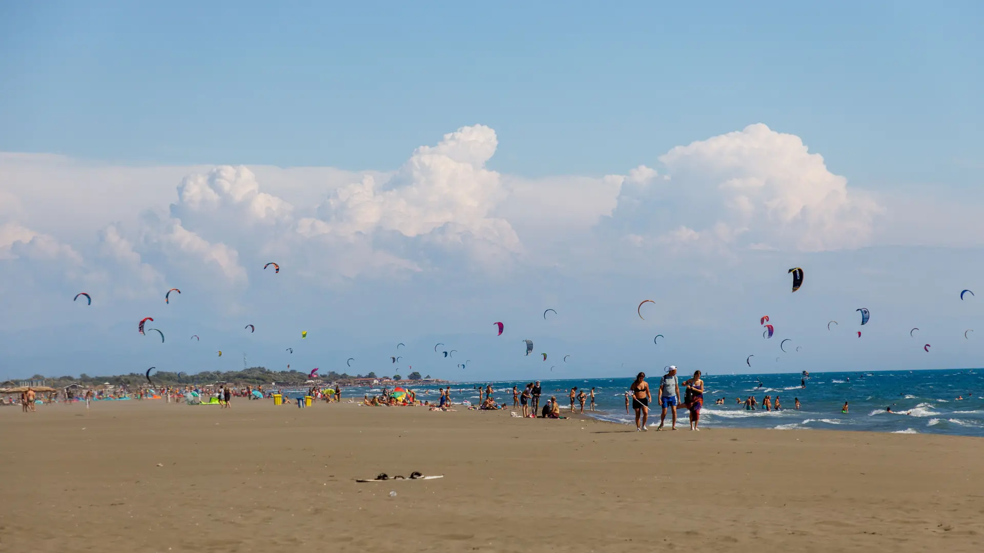 Kitesurfers above a broad sandy beach near Ulcinj in daylight