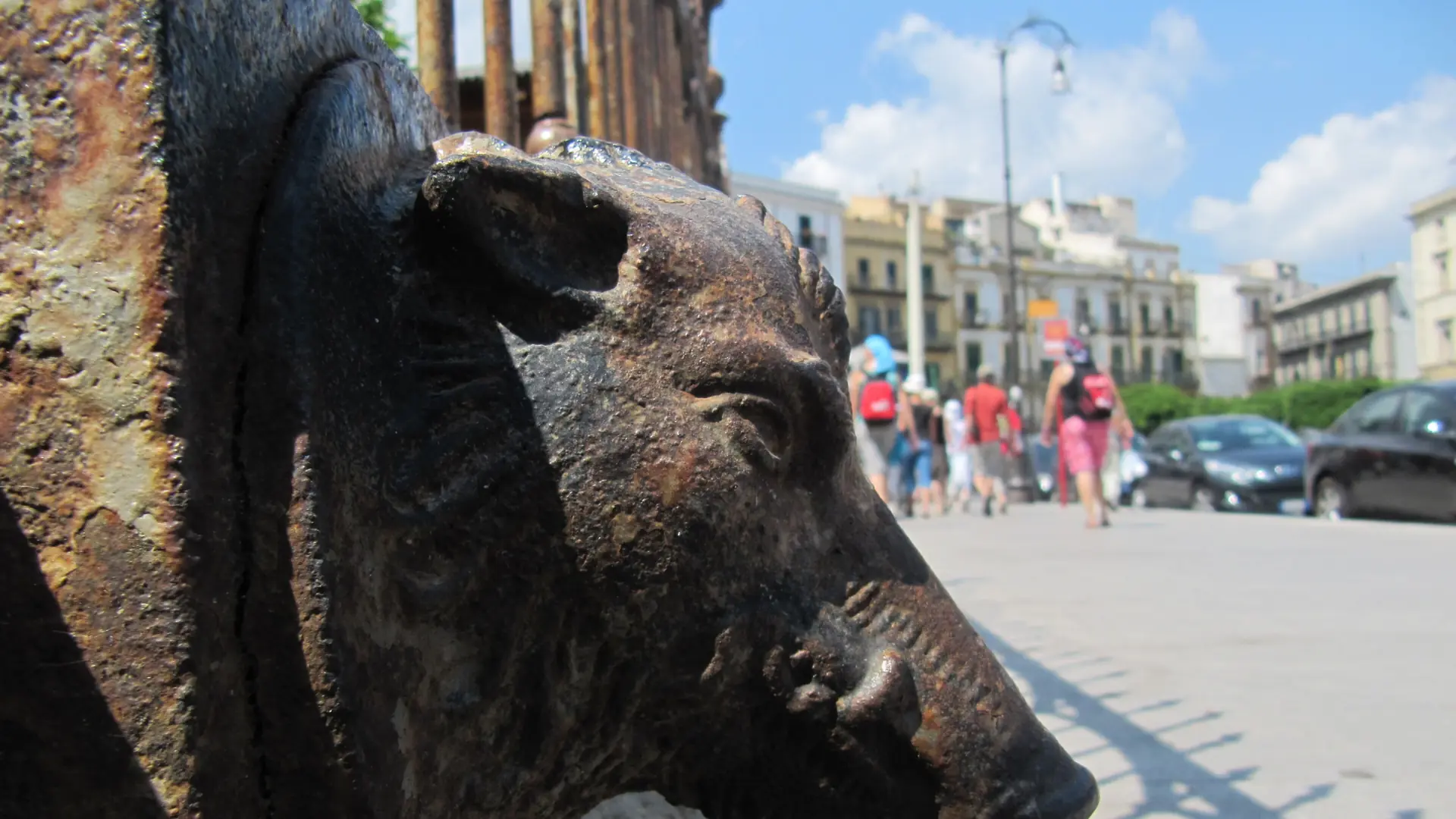 a bronze boar fountain in a sunny Palermo piazza with pastel balconied buildings behind