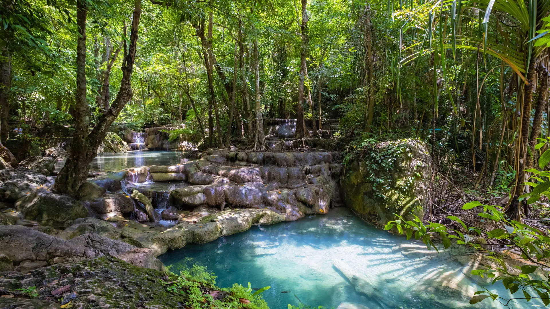 A forest-ringed Thai lagoon below steep limestone slopes