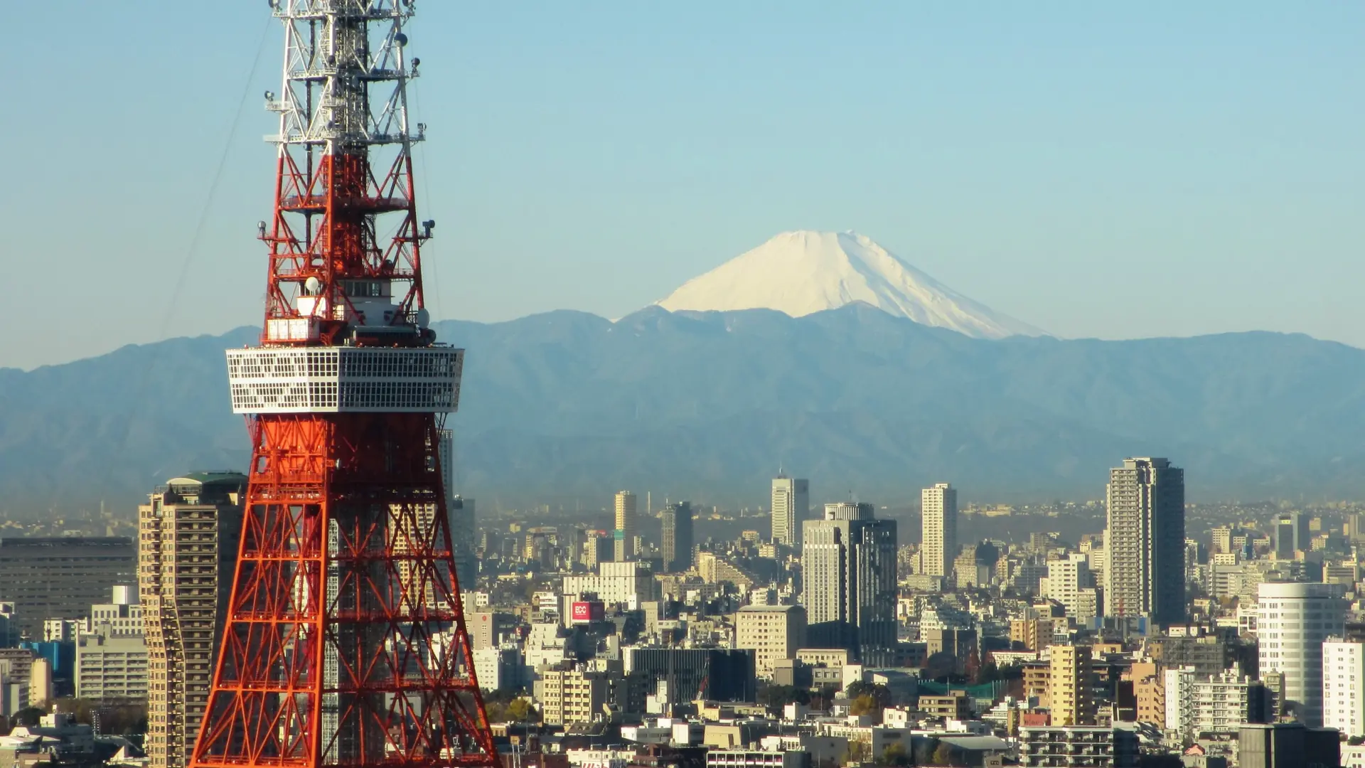 Tokyo skyline with Tokyo Tower, modern towers and Mount Fuji beneath a clear golden sky