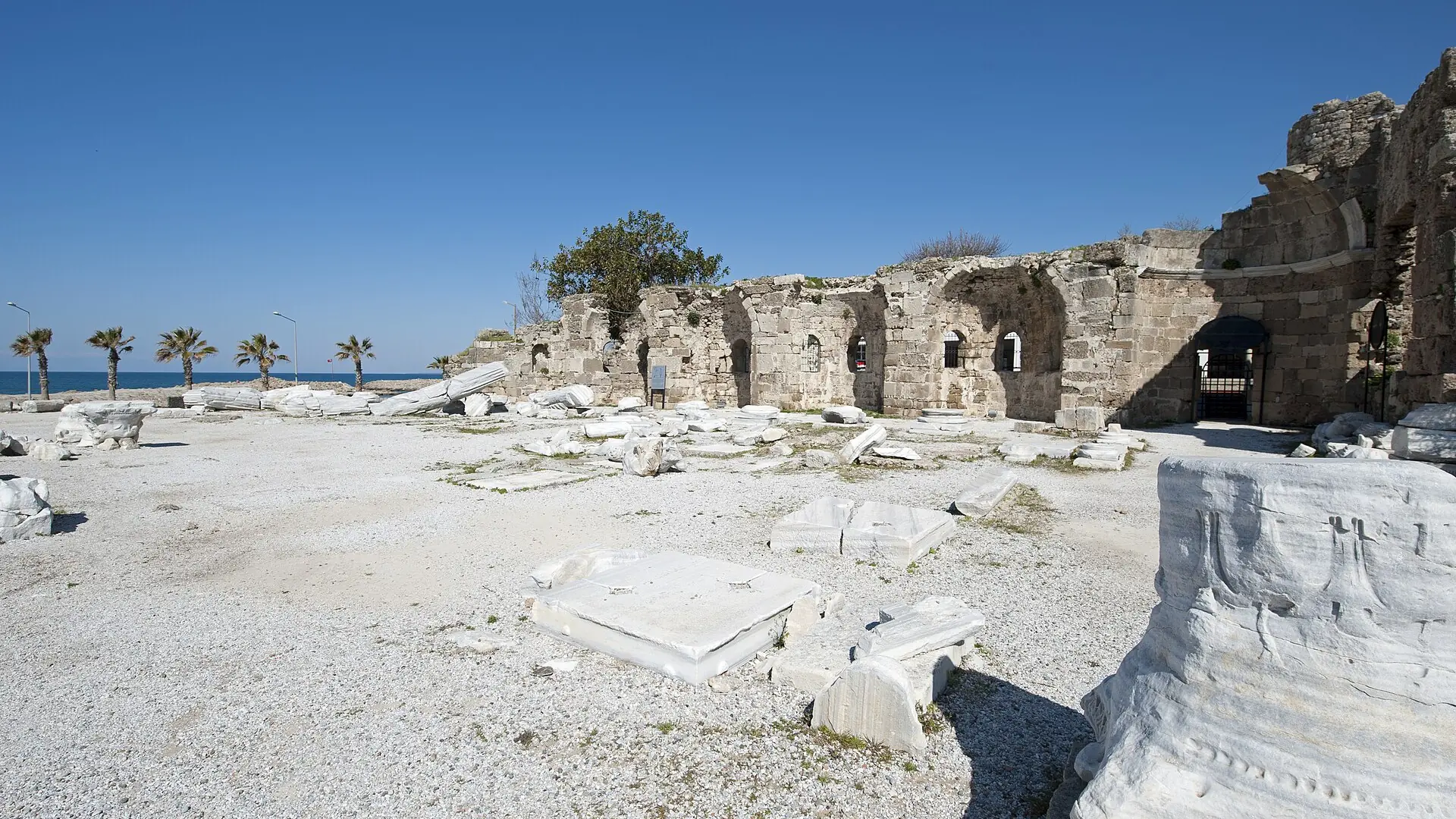 Sunlit coastal ruins and marble fragments beside Side’s Temple of Apollo, shown as a wider city scene