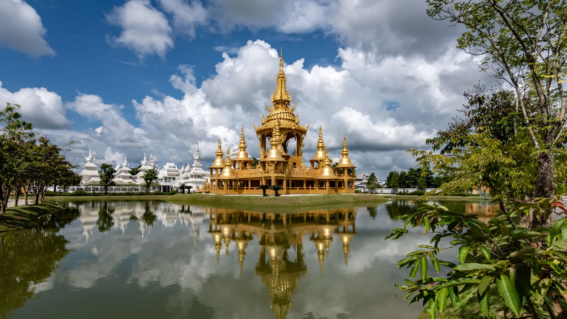 Golden pavilion beside a pond at the White Temple complex, a wider Chiang Rai view