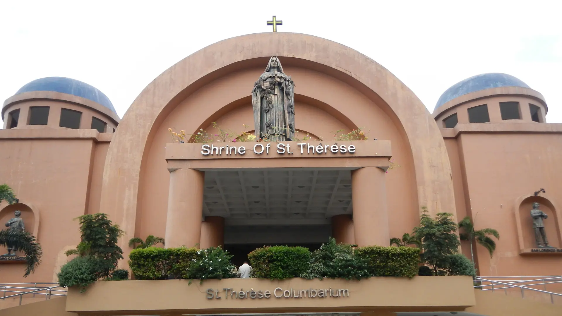 The peach-coloured facade, blue domes and planted entrance of Saint Therese’s shrine in Newport, Pasay, in daylight