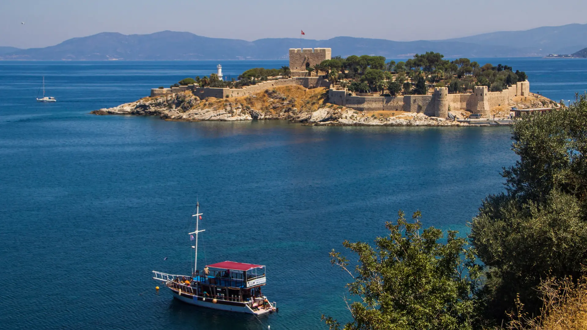 Pigeon Island castle and an excursion boat in Kuşadası, shown as a wider city scene