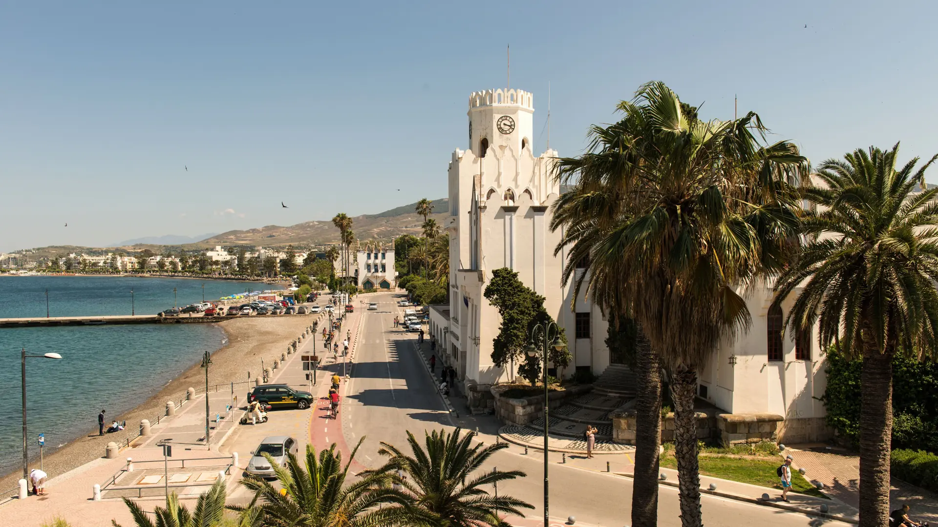 Kalamata's palm-lined seafront and distinctive white waterfront building in summer light