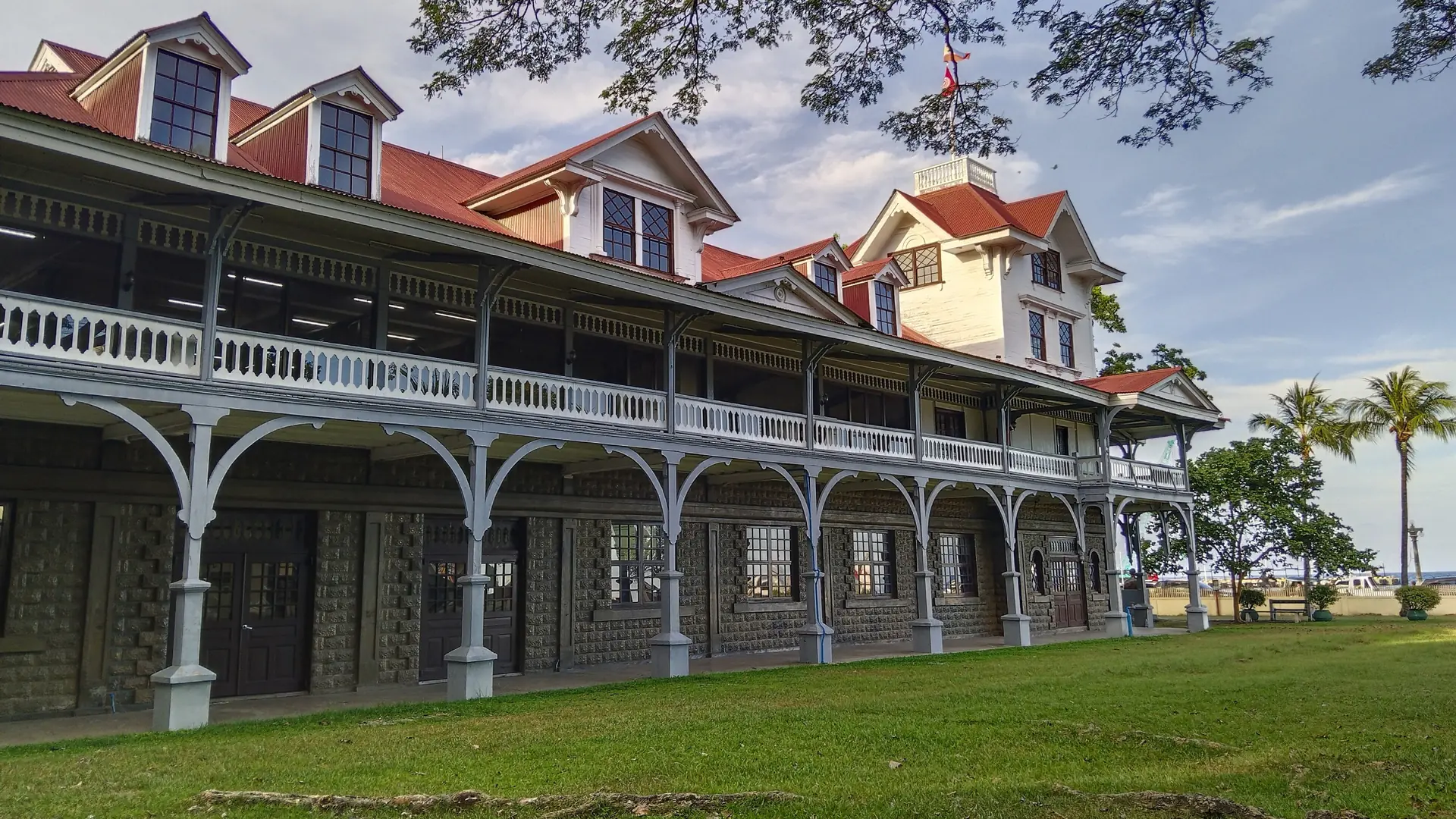 Silliman Hall’s red roofs and long white verandas beside a lawn and shade trees in Dumaguete