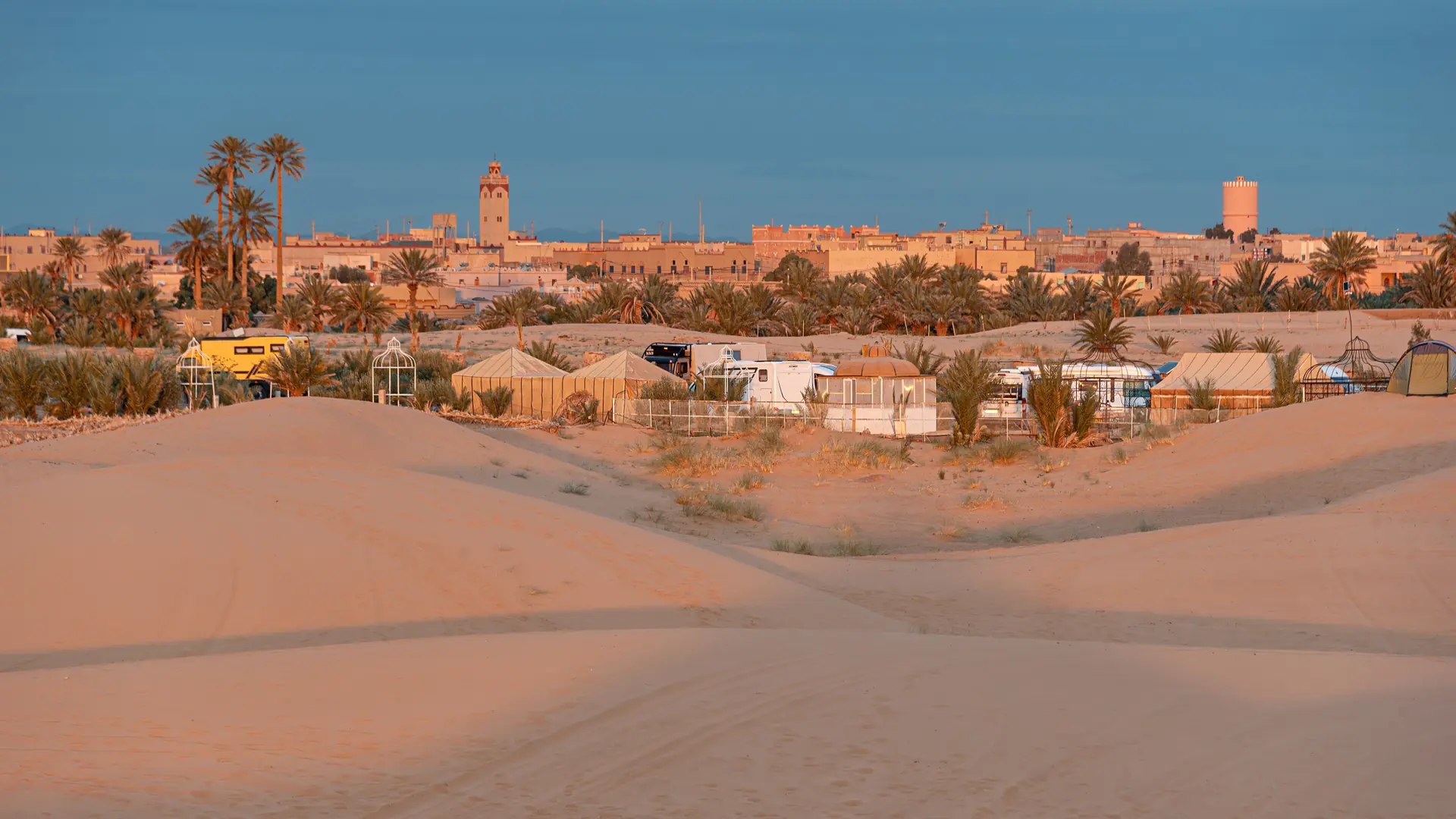 Hassilabied buildings and palms beside dunes in daylight