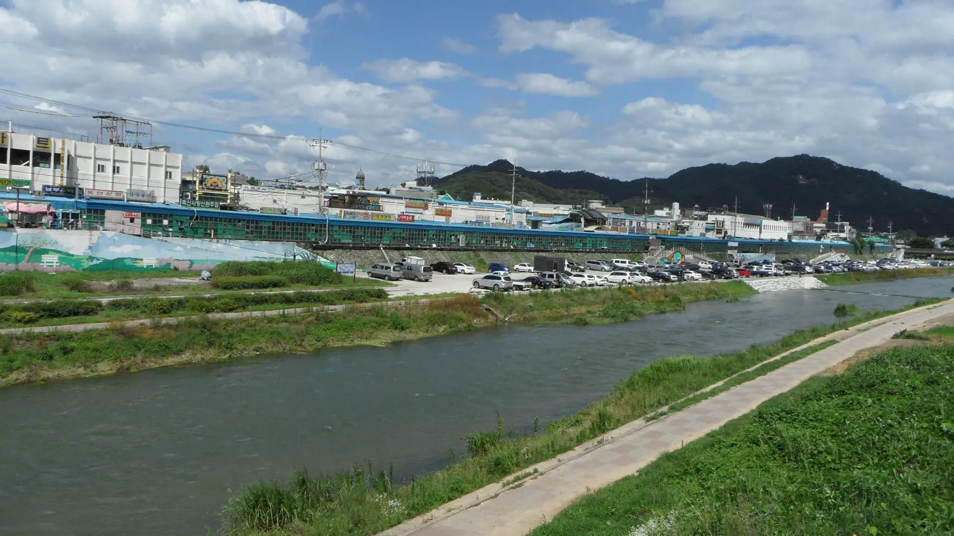 Nambu Market's riverside market building along the Jeonju stream, under a bright blue sky