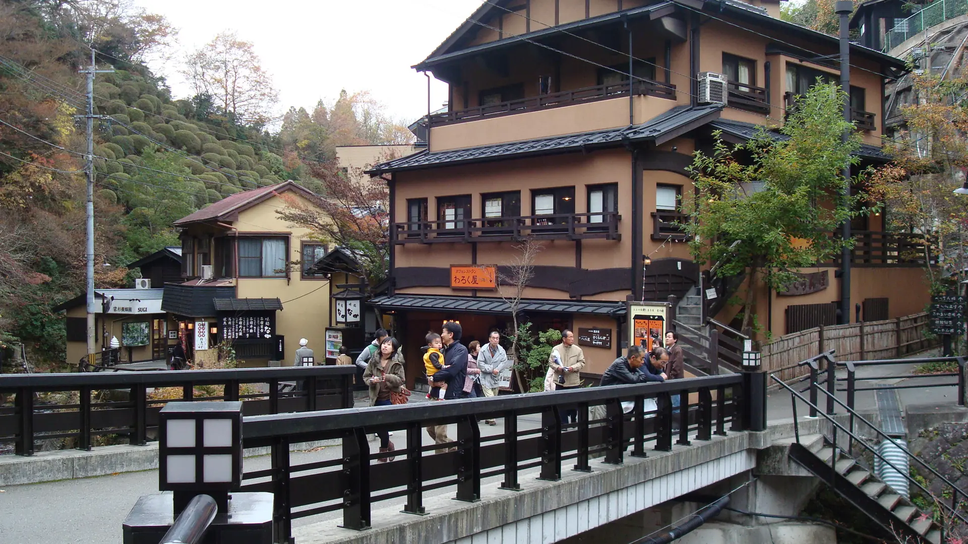 Wooden ryokan and stone bath paths beside Kurokawa’s river