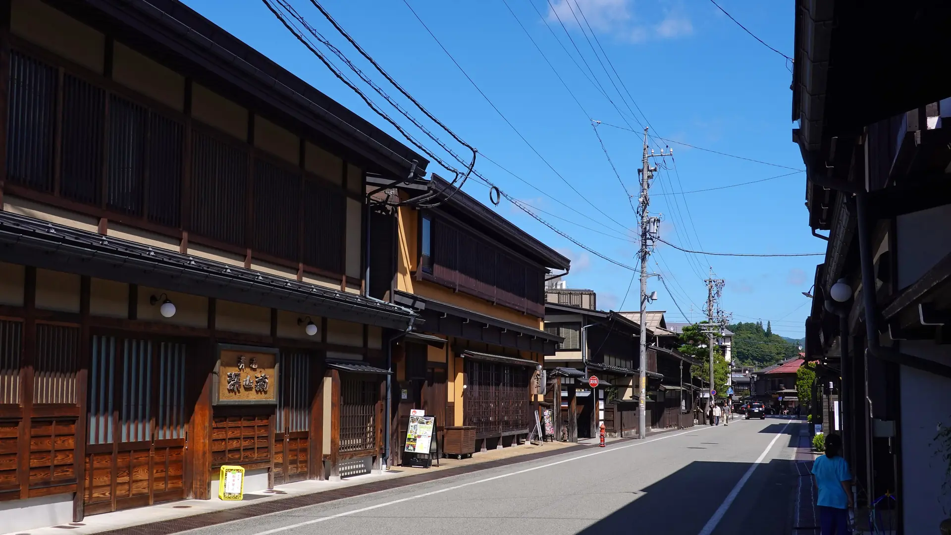 Sunlit wooden shopfronts along a street in Takayama’s Sanmachi old town