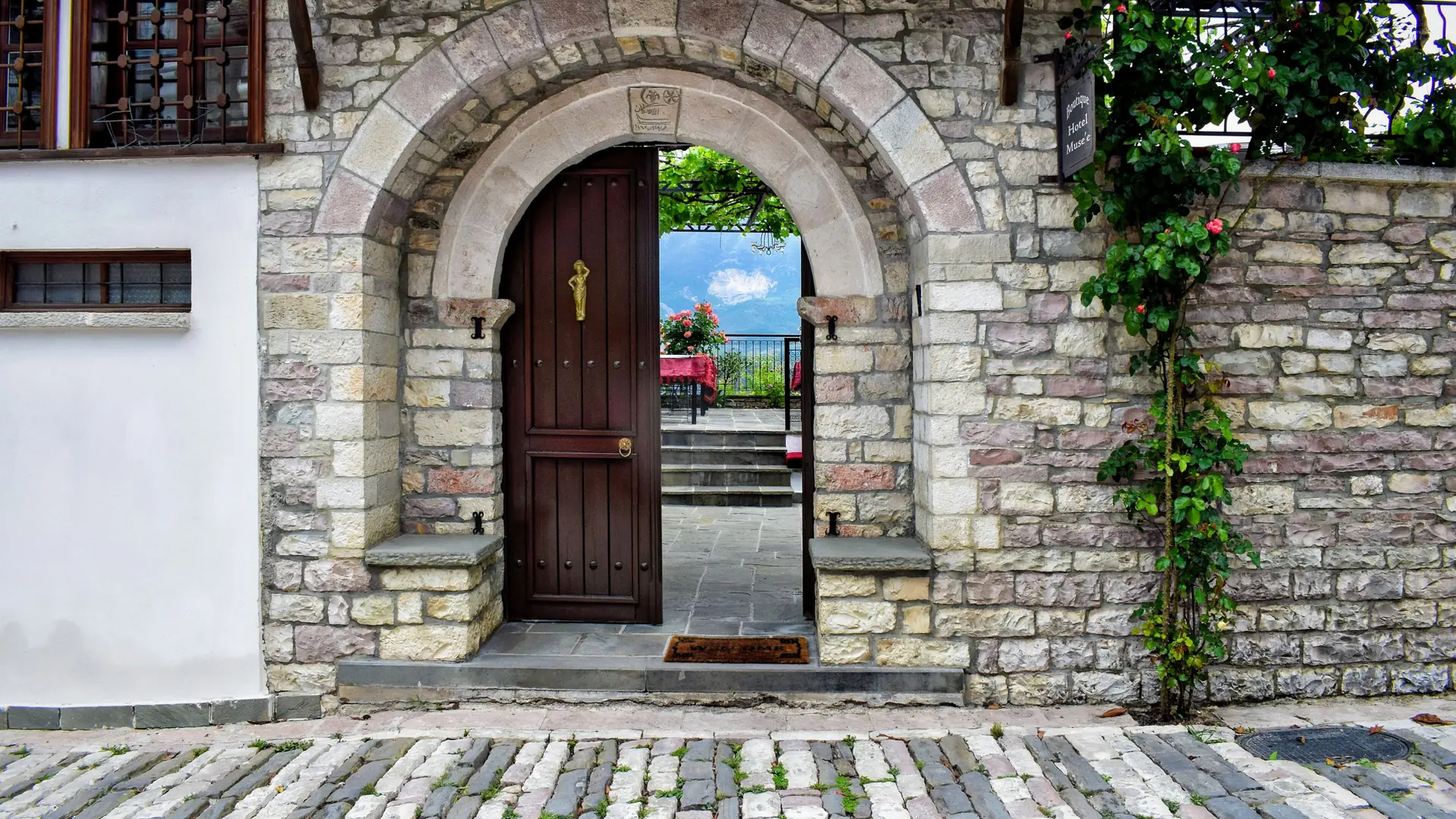 An arched stone gateway and restored stone house on a cobbled lane in Gjirokastër's old town