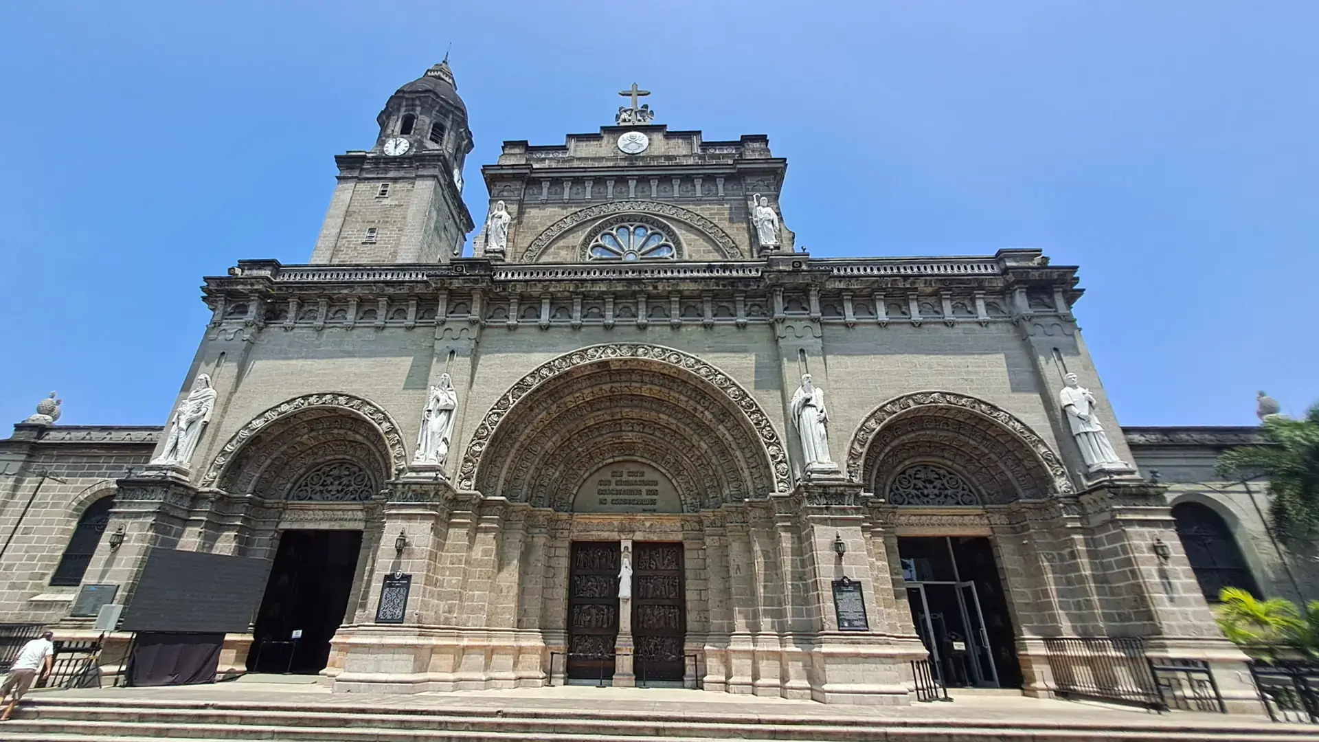 The Romanesque stone facade of Manila Cathedral in Intramuros under a blue sky