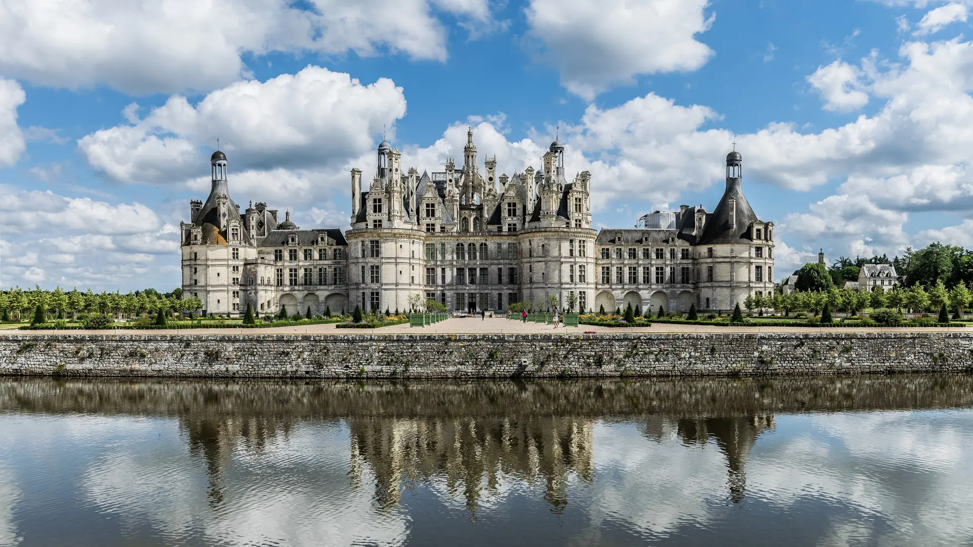 The Renaissance towers of Château de Chambord above its sunlit north-west façade, reflected in the water