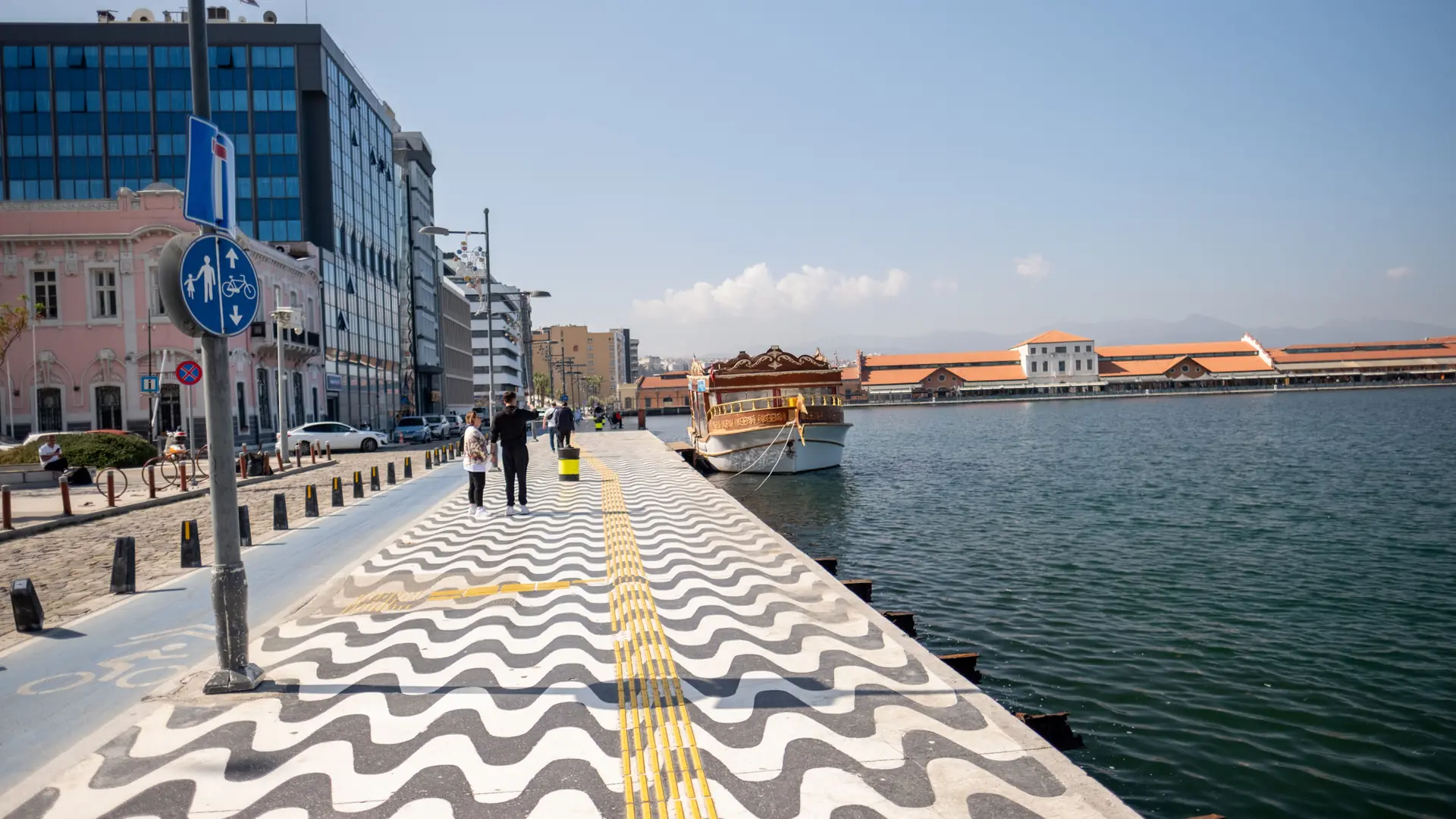 Sunny İzmir Bay promenade beside the red-roofed Konak Pier buildings