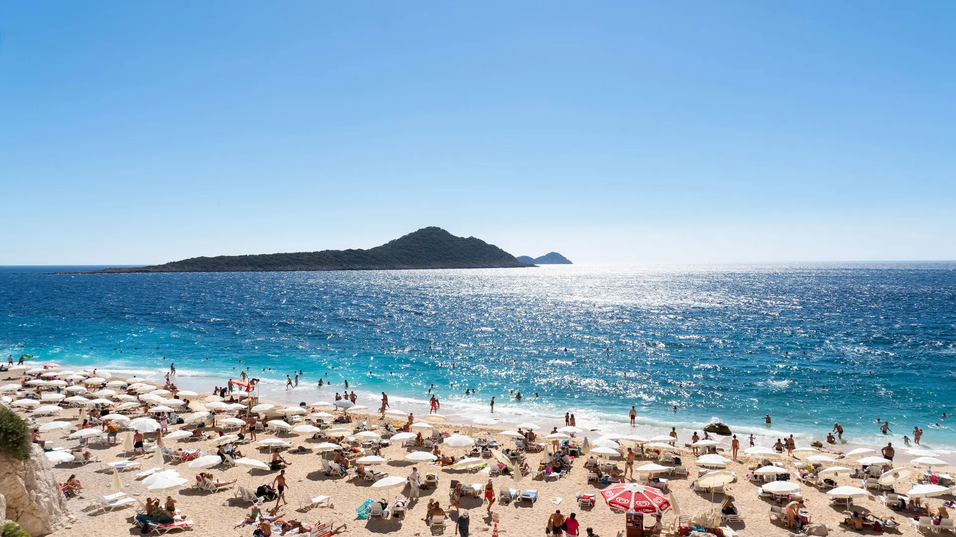 Swimmers and umbrellas on sunny Kaputaş Beach on Turkey’s Lycian coast near Kaş