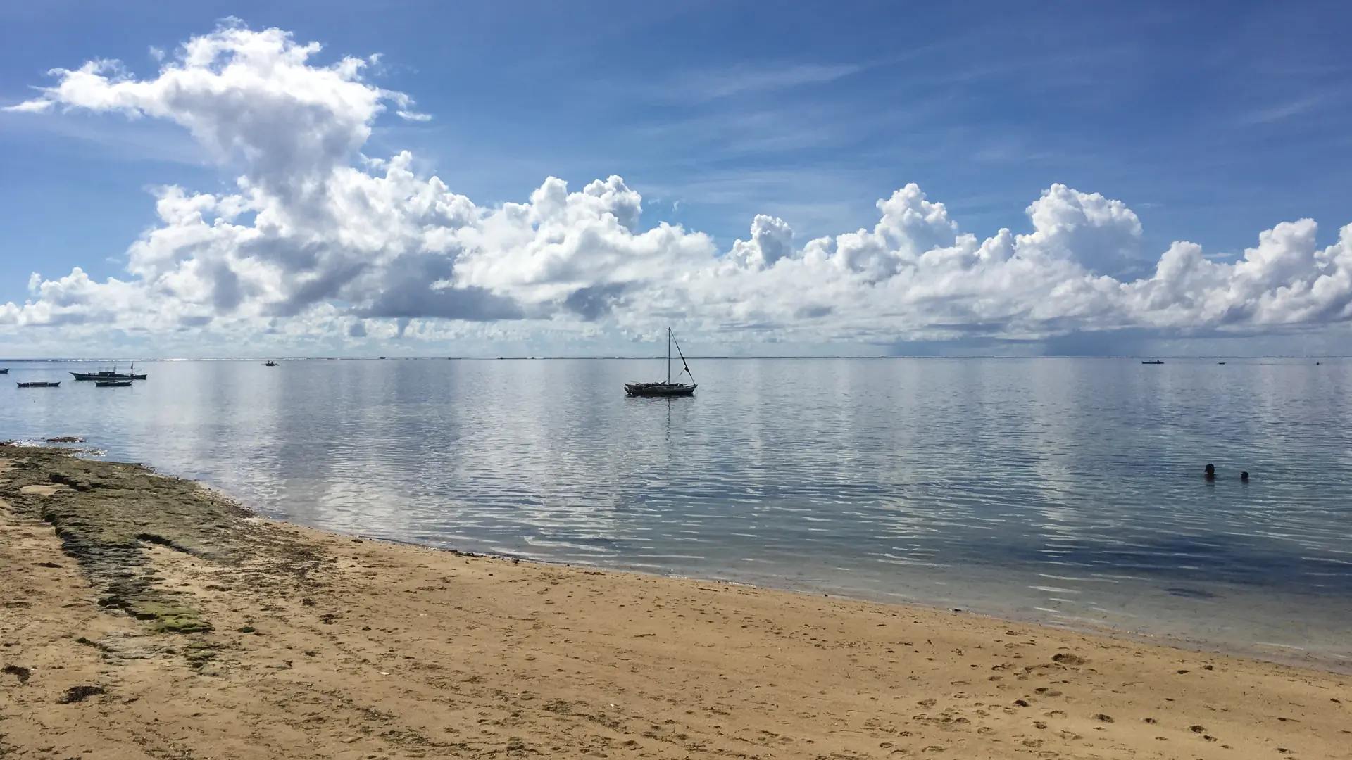 Small boats beyond General Luna’s sandy shoreline under a blue sky, Siargao